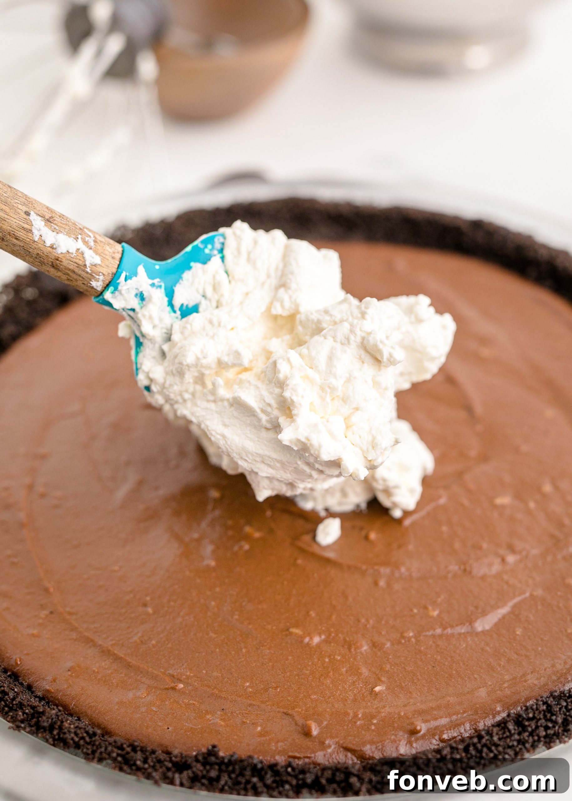 Velvet Chocolate Dream 7 Chocolate Cream Pie being topped with a spoon dropping whipped cream on top