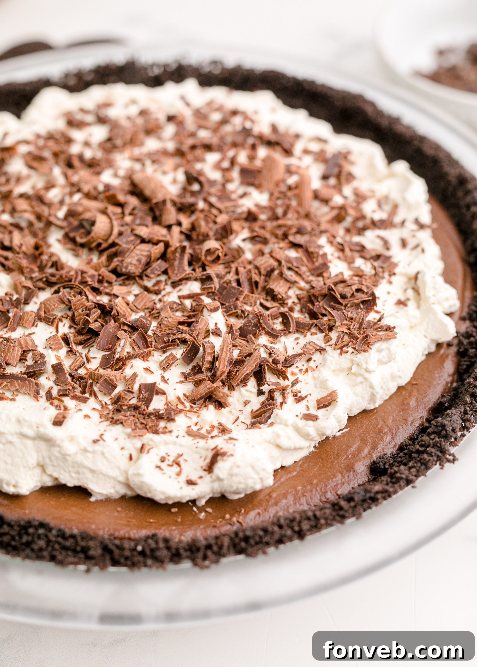 Velvet Chocolate Dream 9 Chocolate Cream Pie topped with real whipped cream and sprinkled with chocolate shavings, shown at an angle
