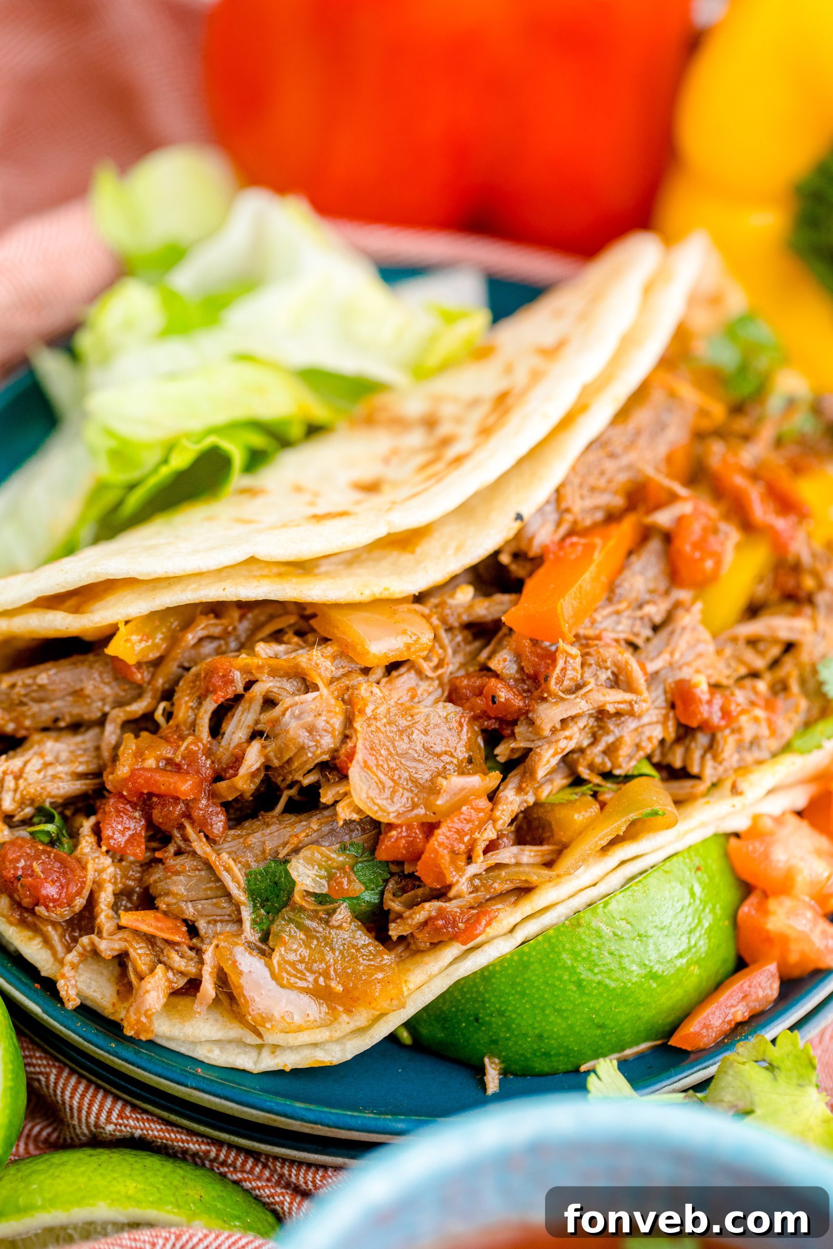 Steak Fajitas wrapped in a tortilla with lettuce piled next to it and limes with salsa