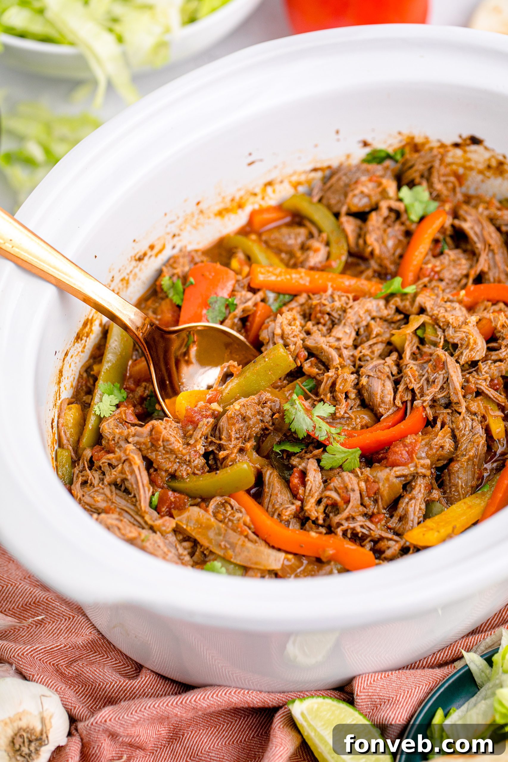 Steak Fajitas in a white crock pot with a gold spoon