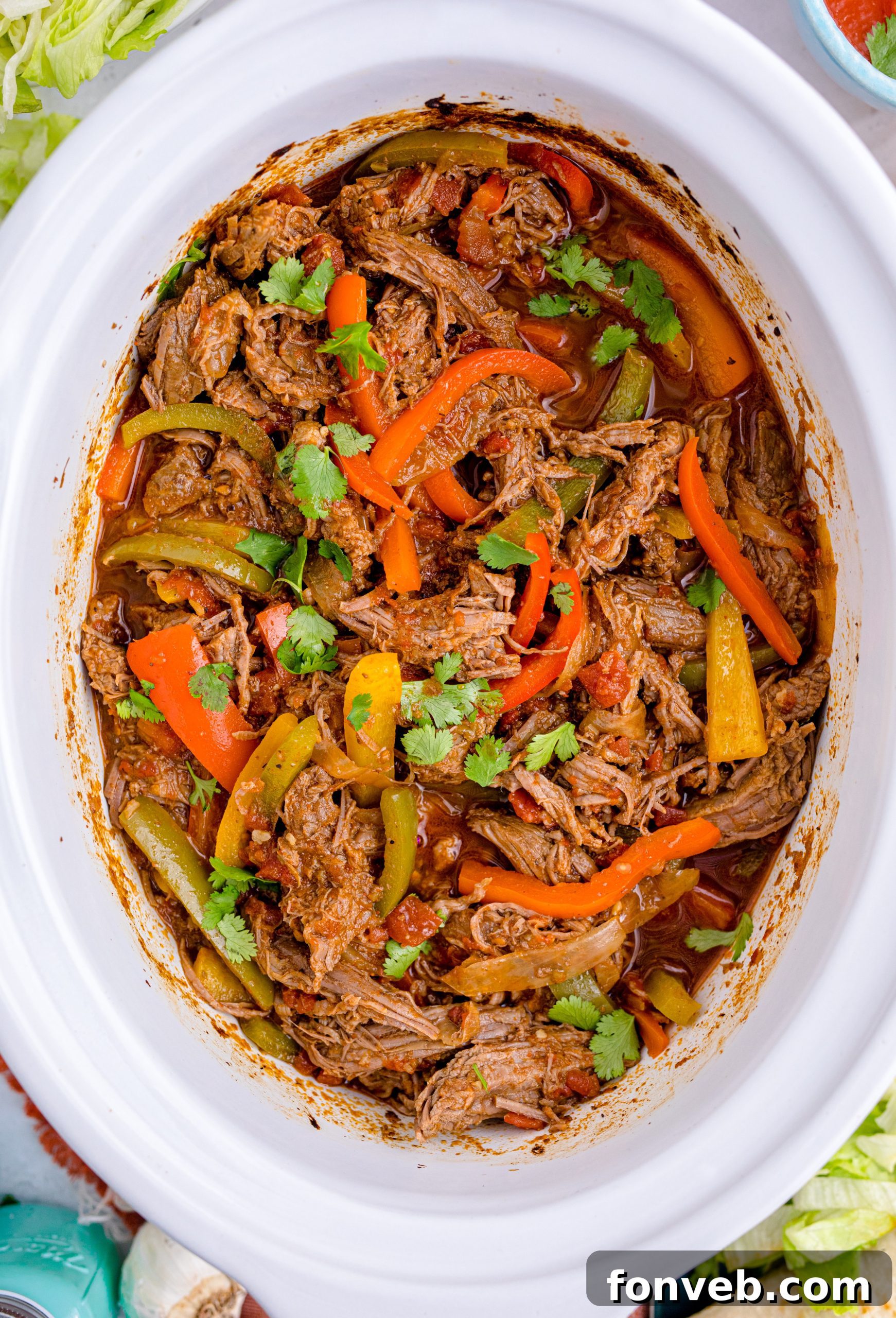 Steak Fajitas in a white crockpit with red and green peppers mixed in