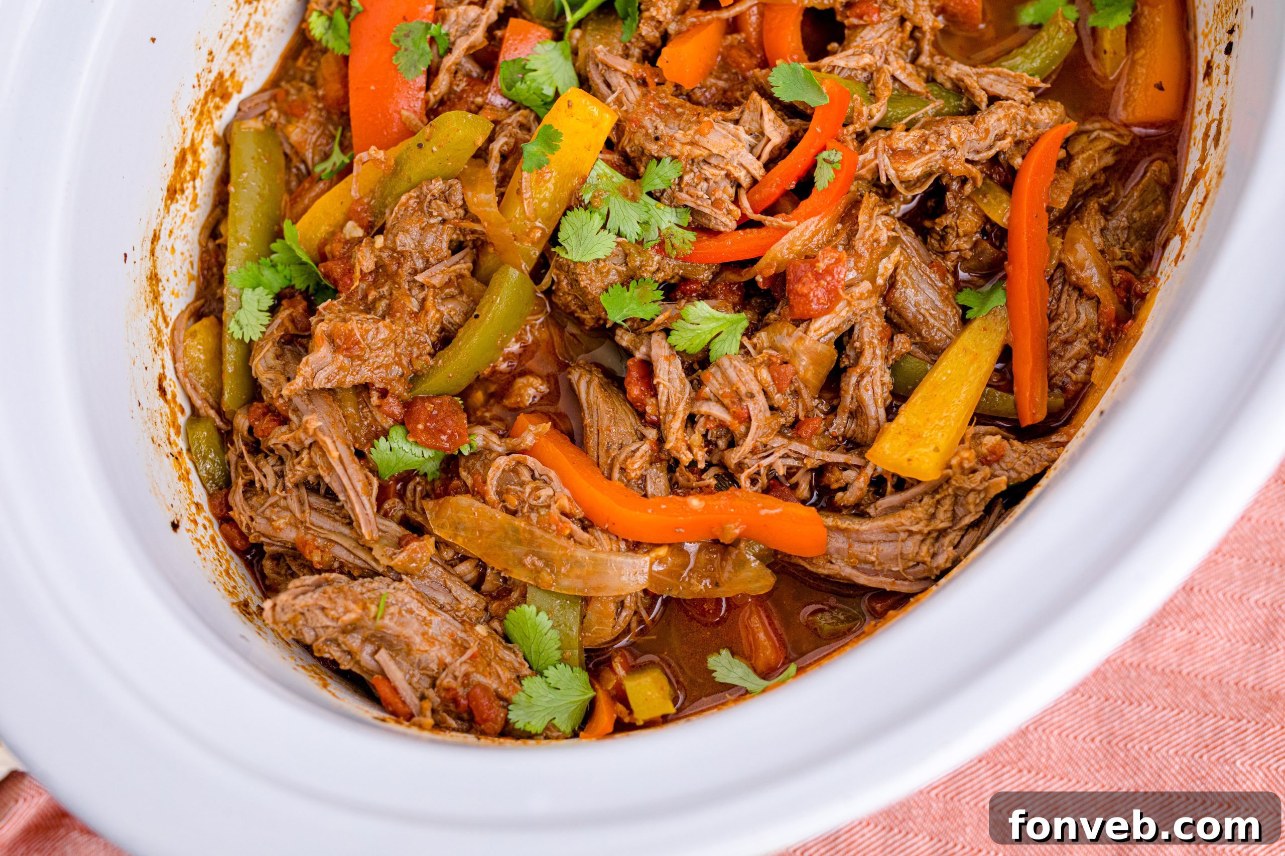 Steak Fajitas in a white crockpit with red and green peppers mixed in