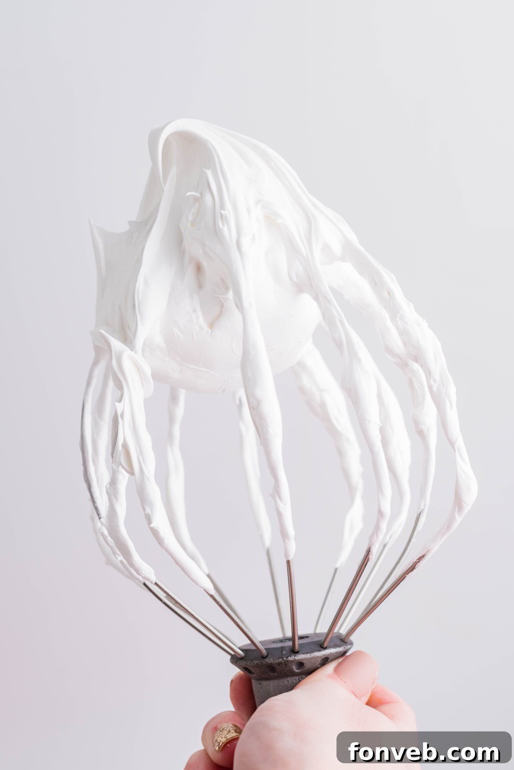 Marshmallow frosting on a whisk, showcasing its fluffy texture