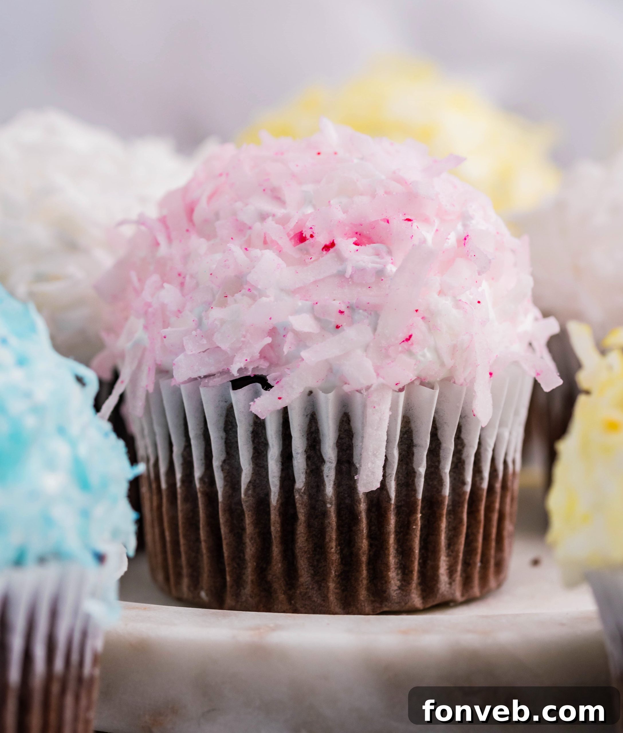 Chocolate cupcake with pink coconut shavings & marshmallow frosting on a marble platter