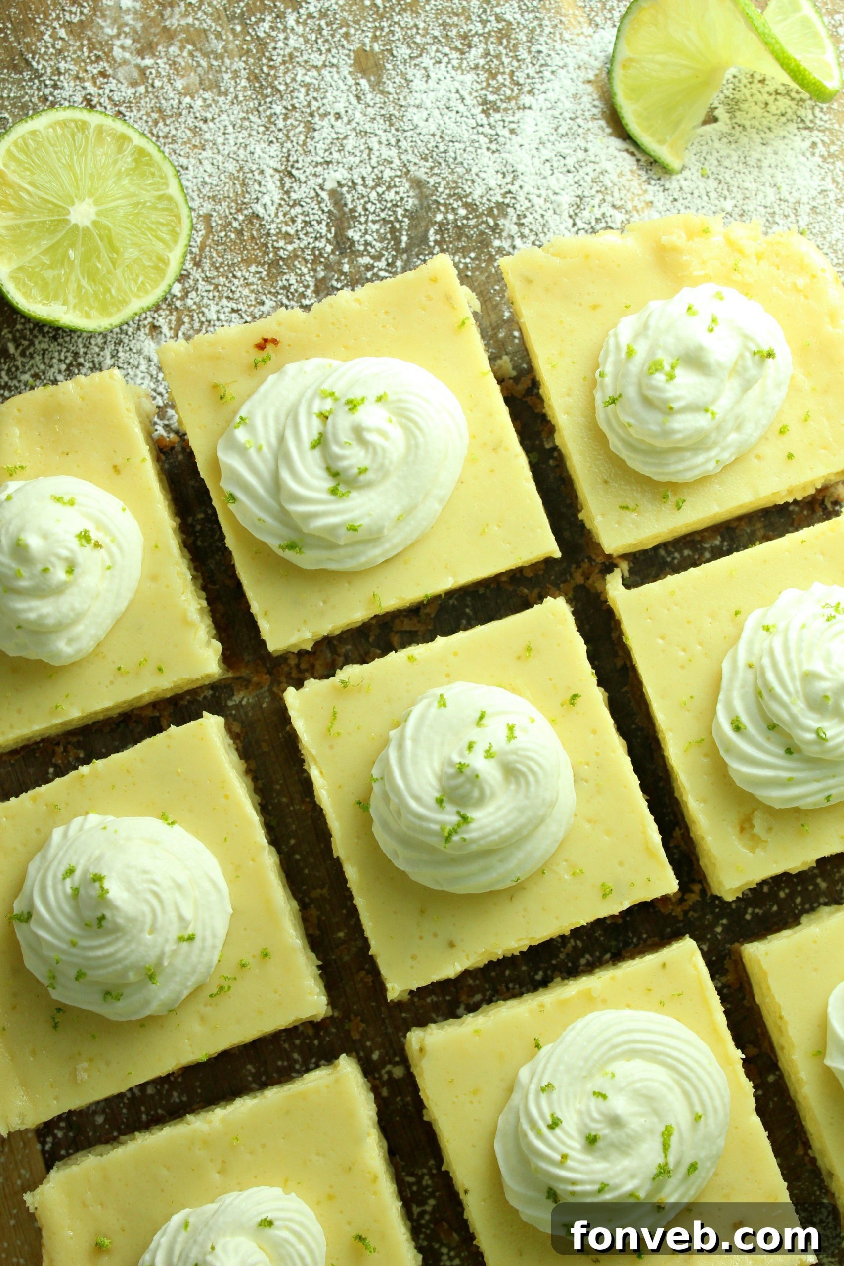 Key Lime Bars with lime whipped cream topped with lime zest on a baking sheet
