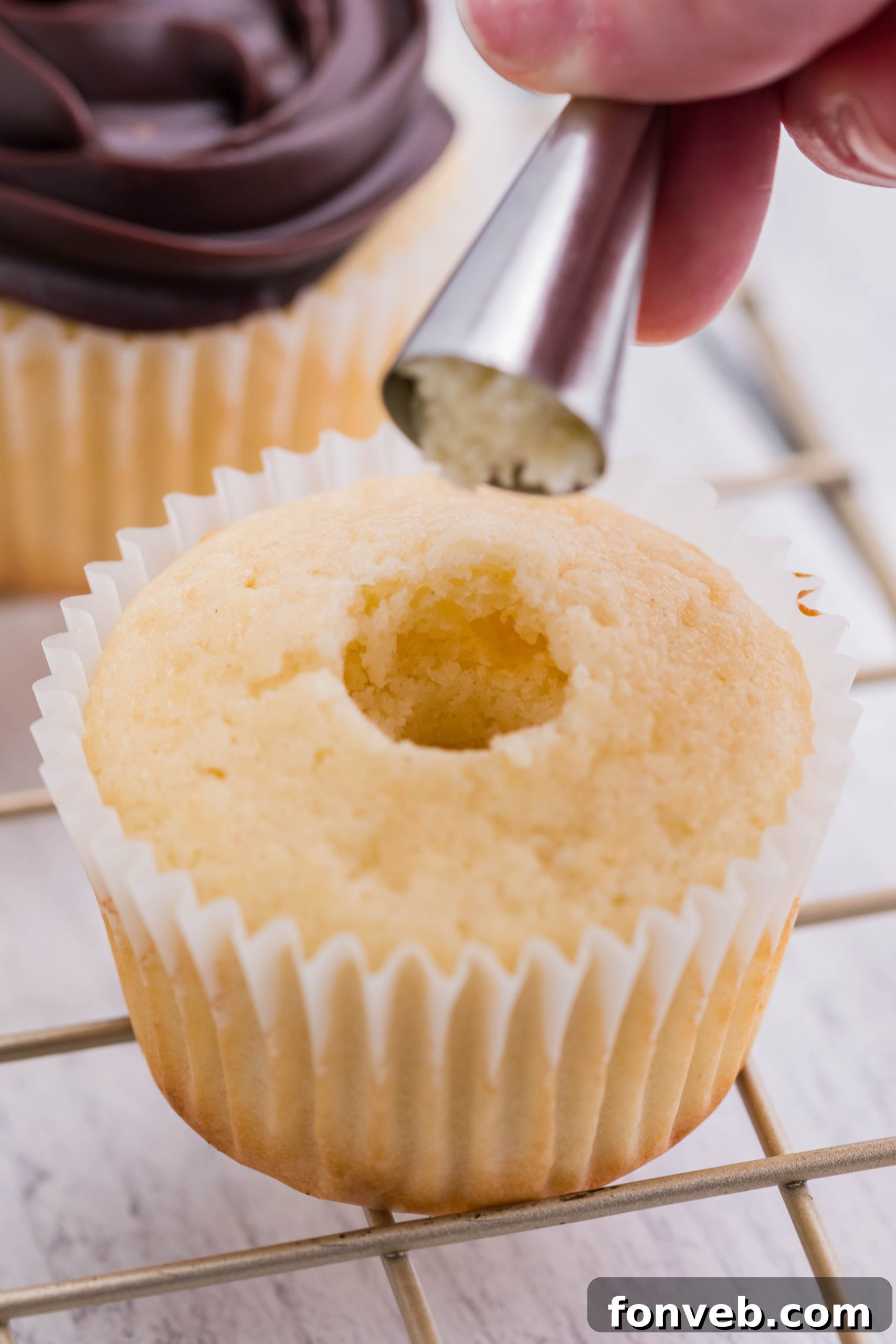 removing a piece of the cake from the center of the boston cream cupcake to be able to add the filling