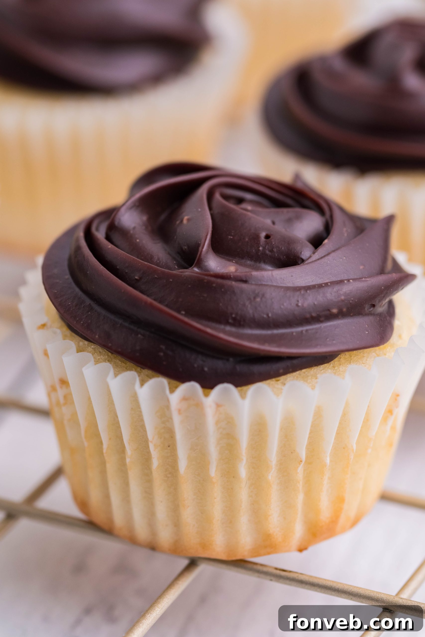 side shot of Boston Cream Cupcakes on a cooling metal rack