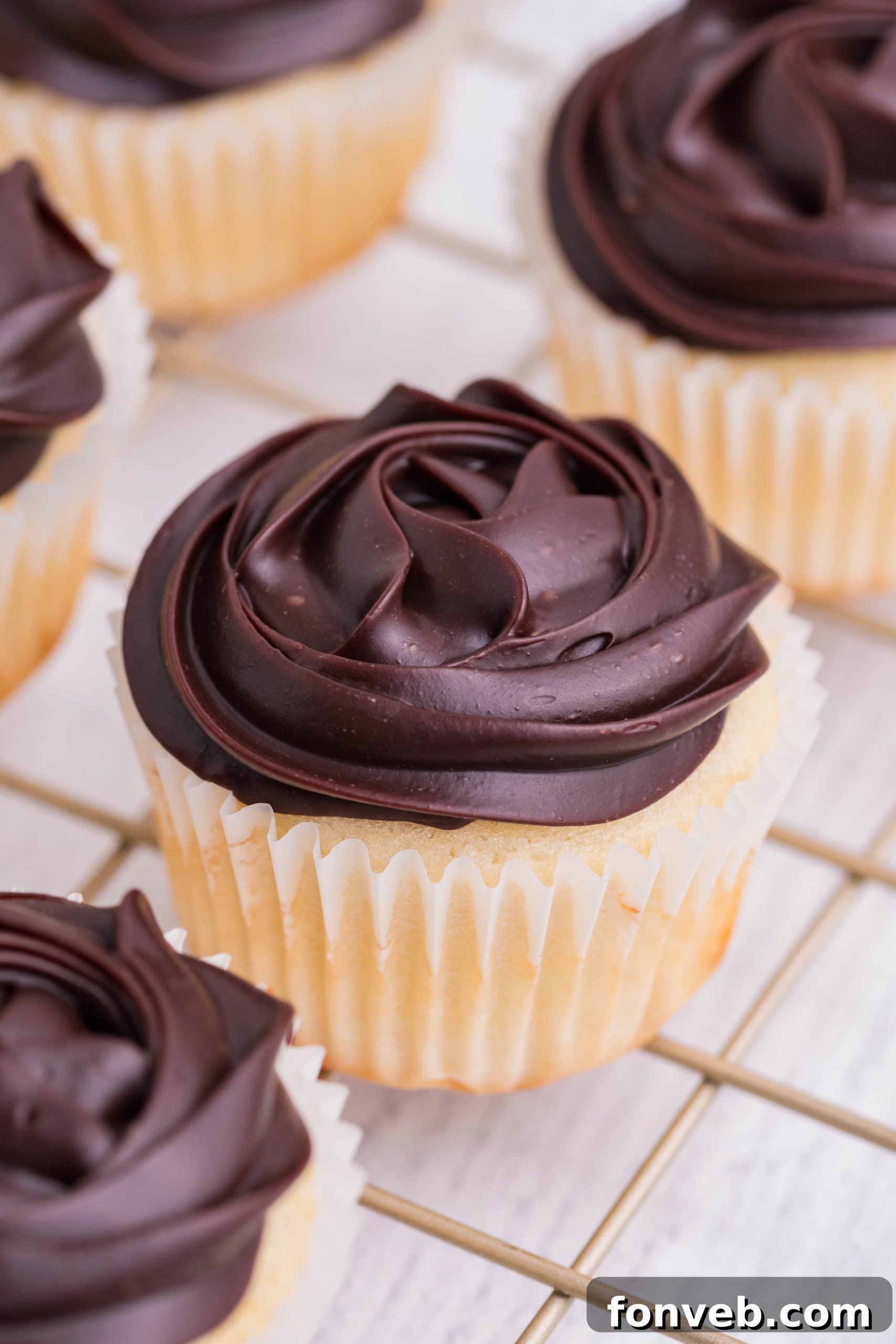 side shot of Boston Cream Cupcakes on a cooling metal rack