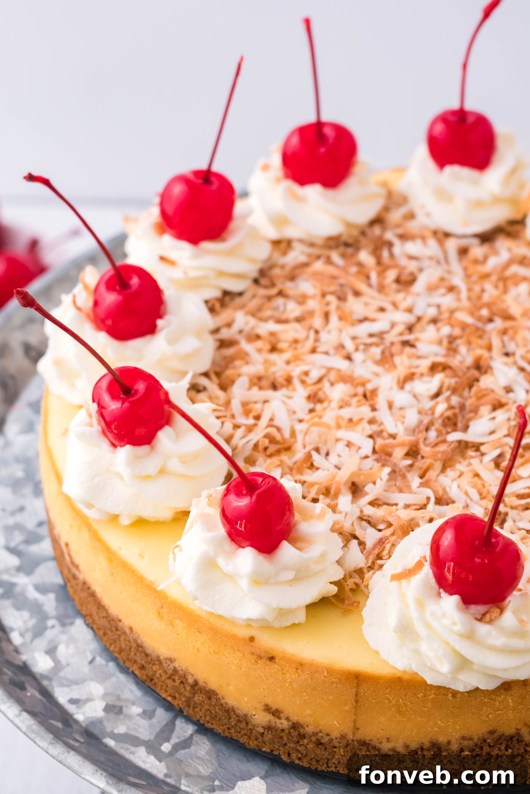 The full Coconut Cheesecake on its silver cake dish, a perfect dessert centerpiece.