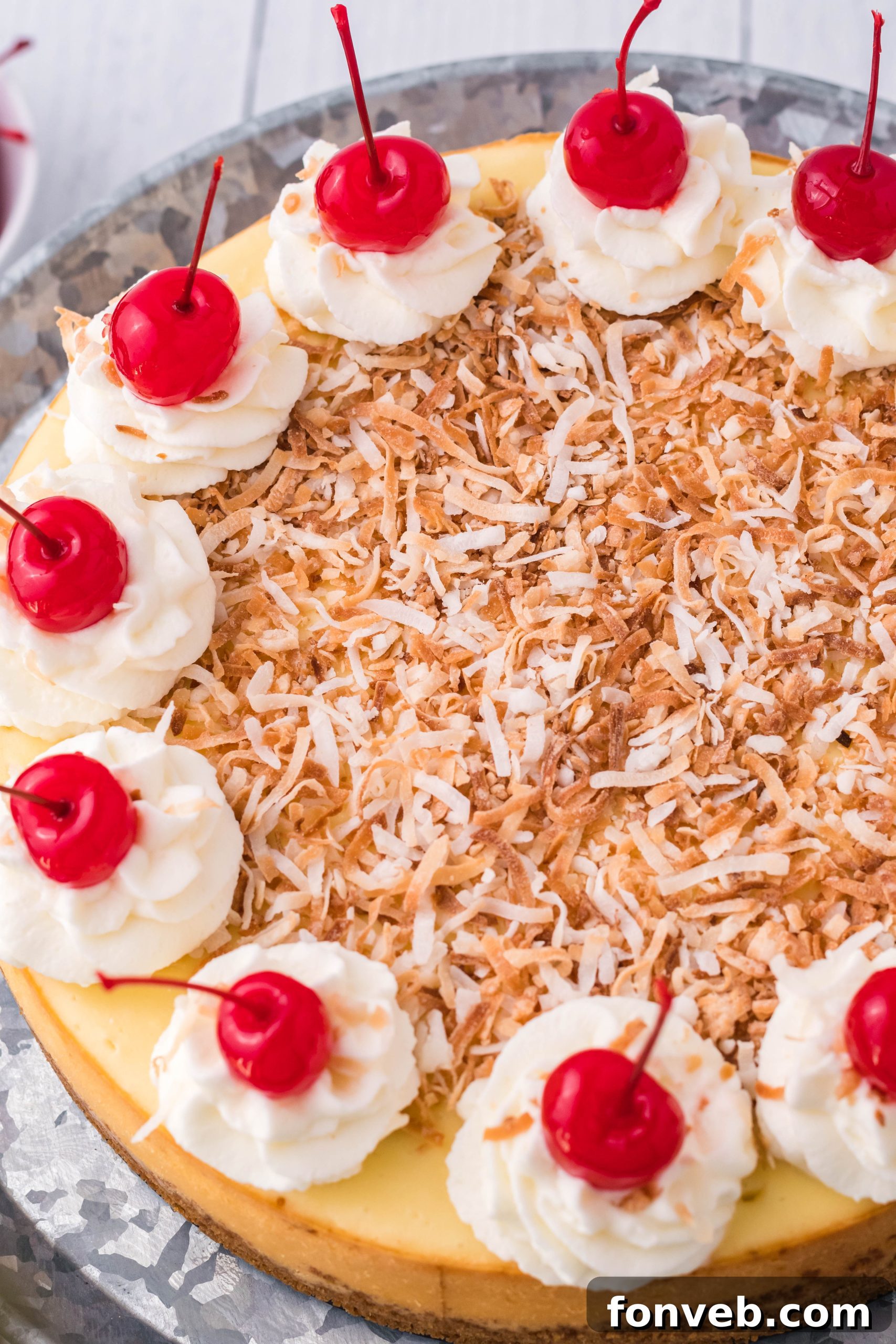Another overhead shot of the elegant Coconut Cheesecake resting on a silver cake dish, ready for serving.
