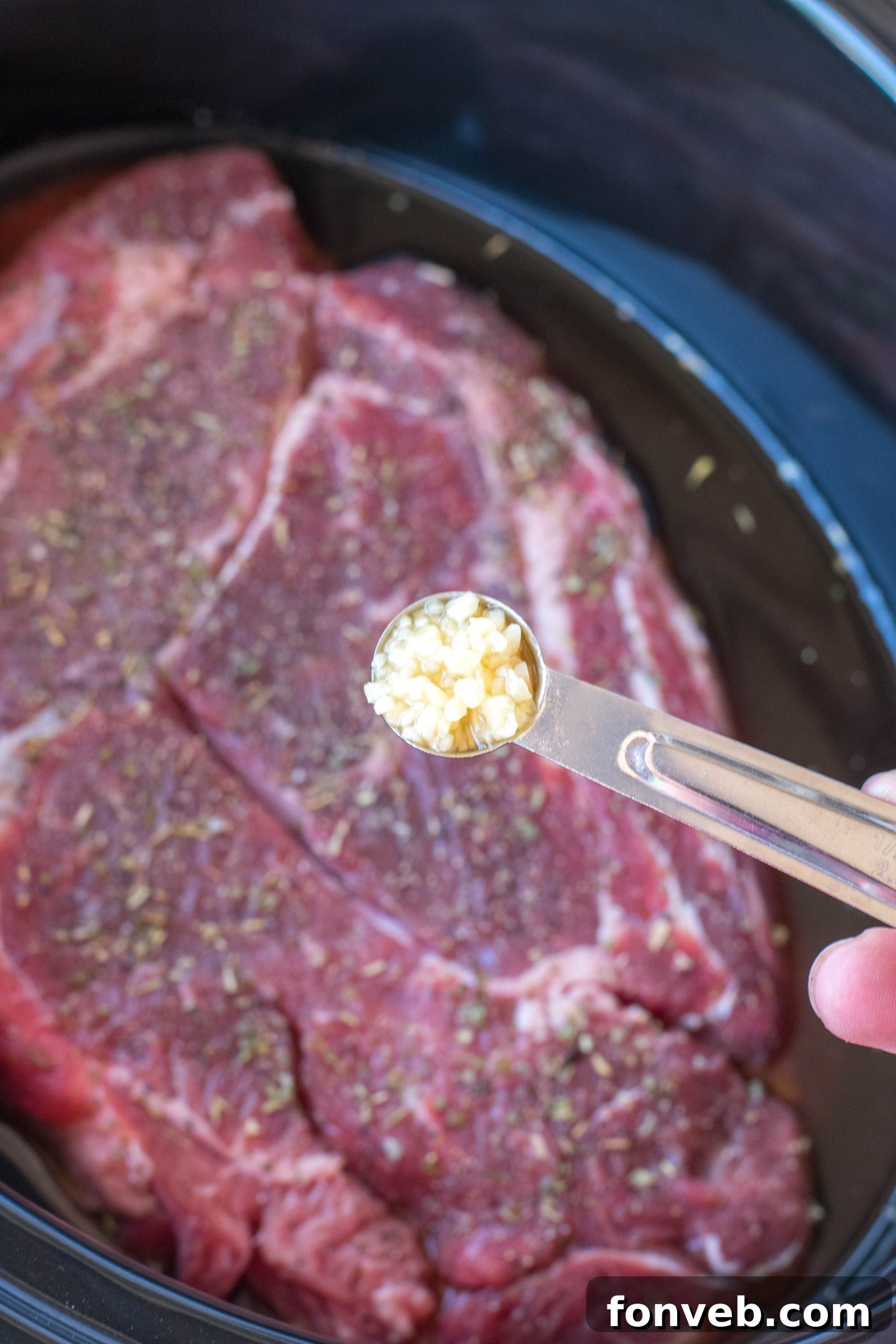 crock pot chuck roast in a black crock pot uncooked