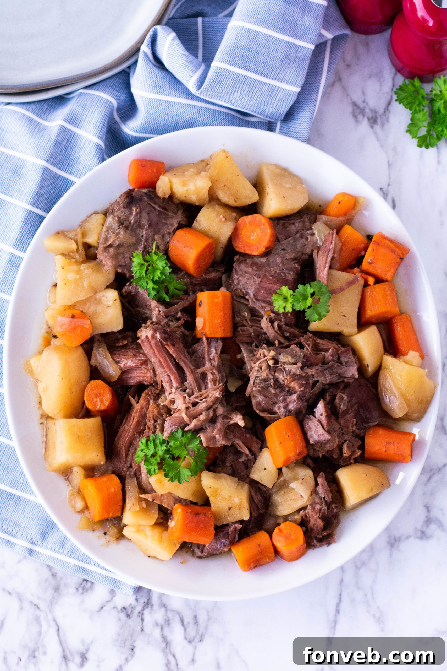 crock pot chuck roast on a plate with potatoes and carrots overhead shot
