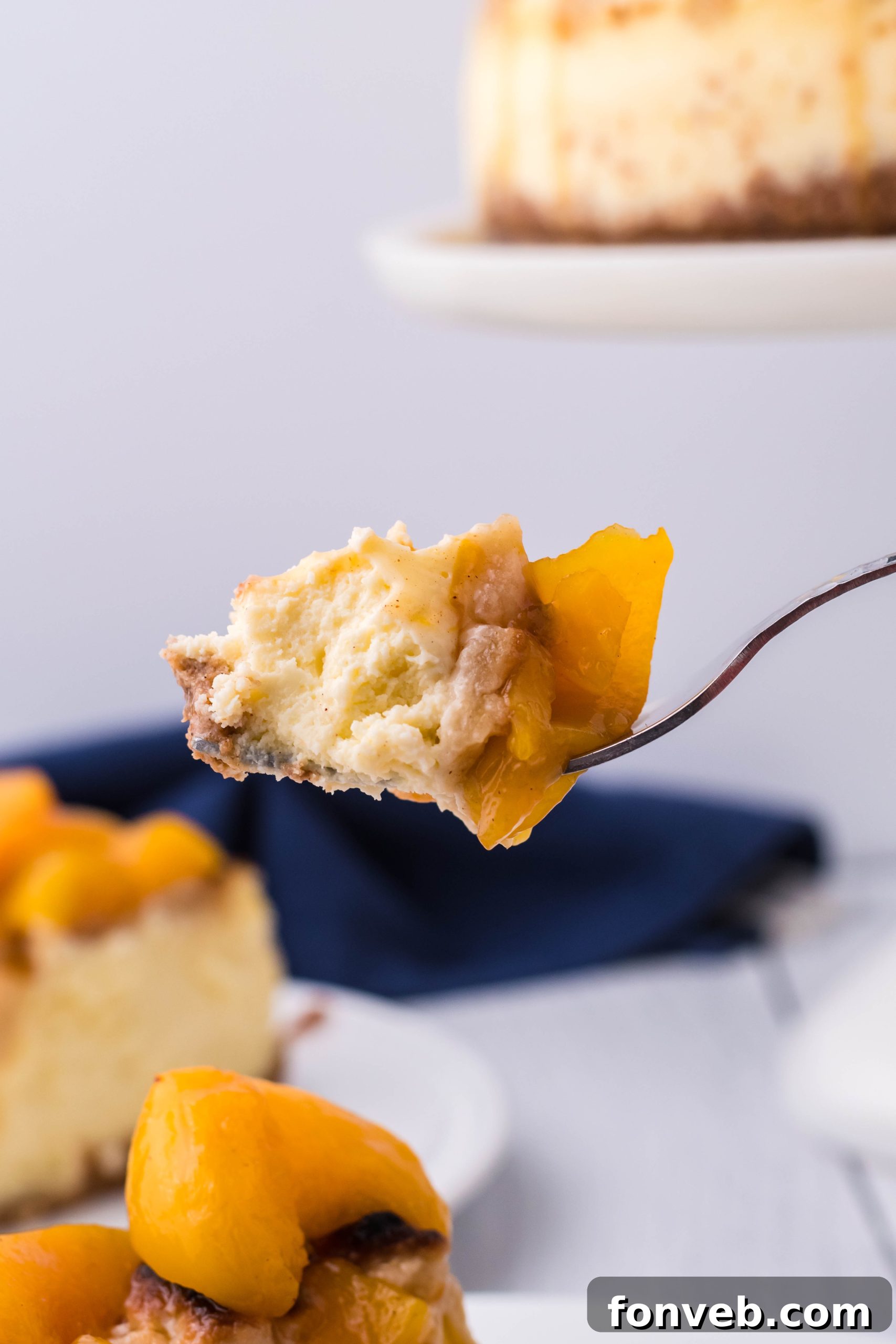 A fork holding a bite-sized piece of Peach Cobbler Cheesecake, ready to be enjoyed.