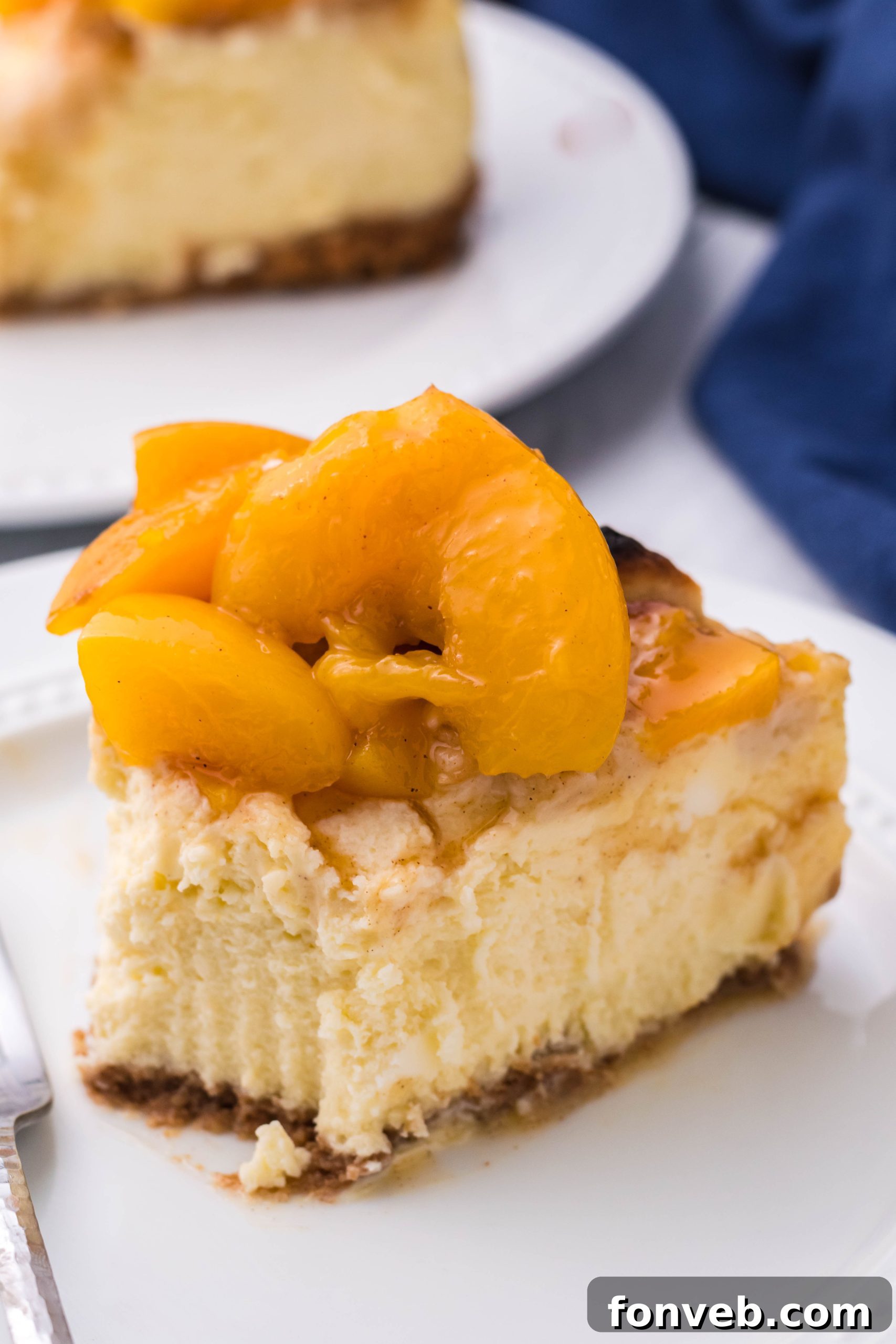 A top-down view of a slice of Peach Cobbler Cheesecake on a white plate, showing its delicious layers.
