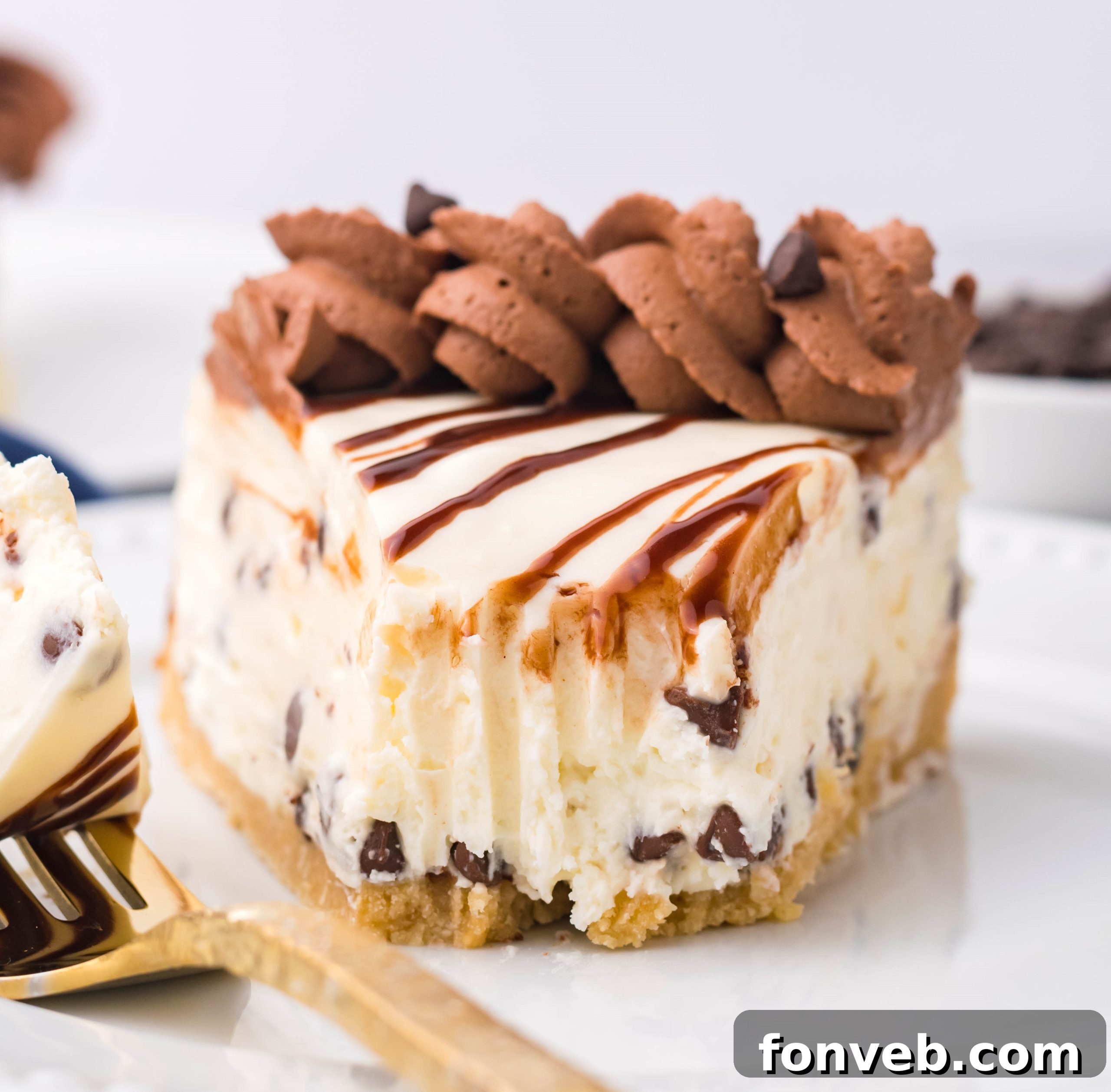 Chocolate Chip Cheesecake on a white plate with a bite taken out with a gold fork on the plate