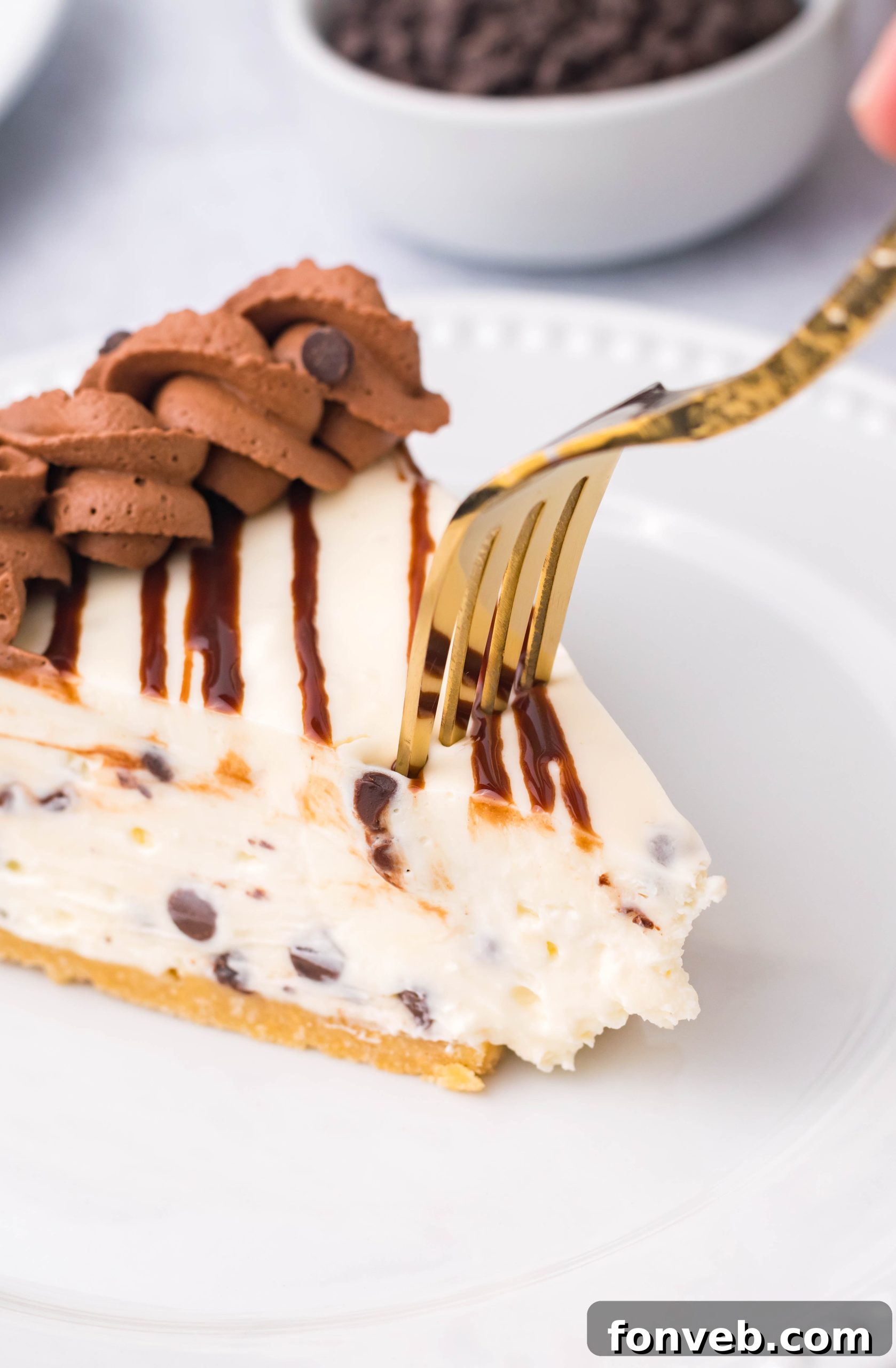 Chocolate Chip Cheesecake on a white plate with a gold fork cutting into the piece