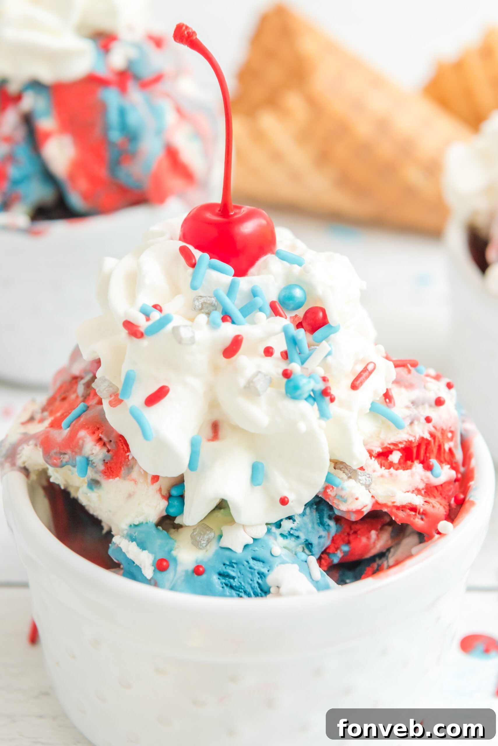 Red, White & Blue Ice Cream in a white bowl topped with whipped cream and a cherry