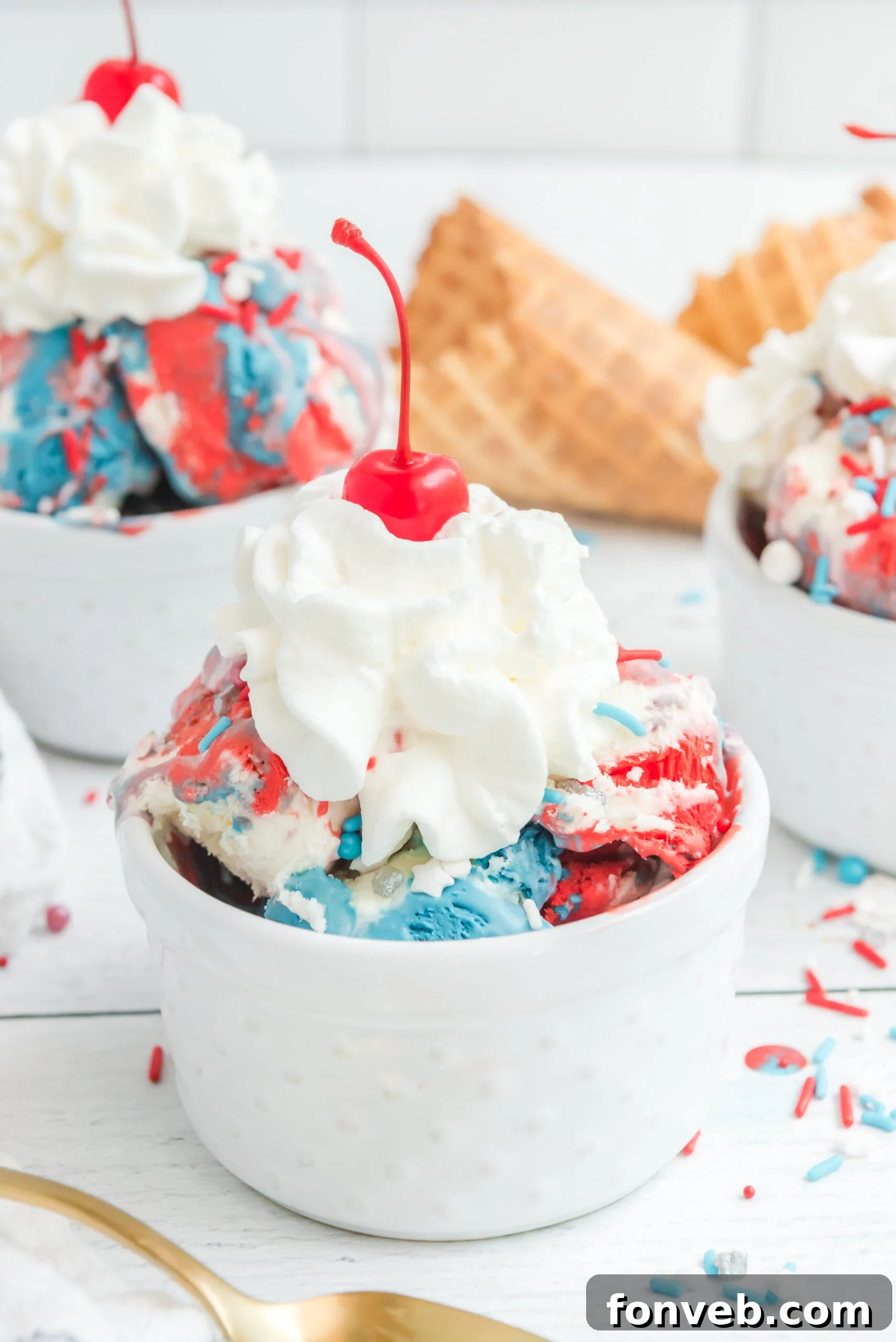 Red, White & Blue Ice Cream in a white bowl topped with whipped cream and a cherry