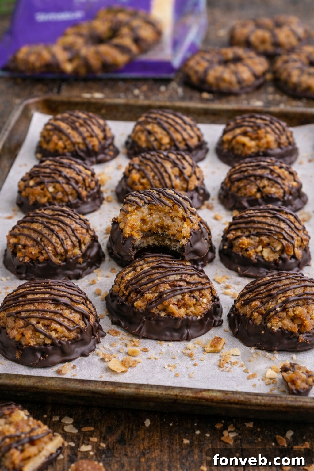 A close-up of finished Samoa Bites on a parchment paper-lined baking sheet, showcasing their rich chocolate coating and delicate caramel drizzle.