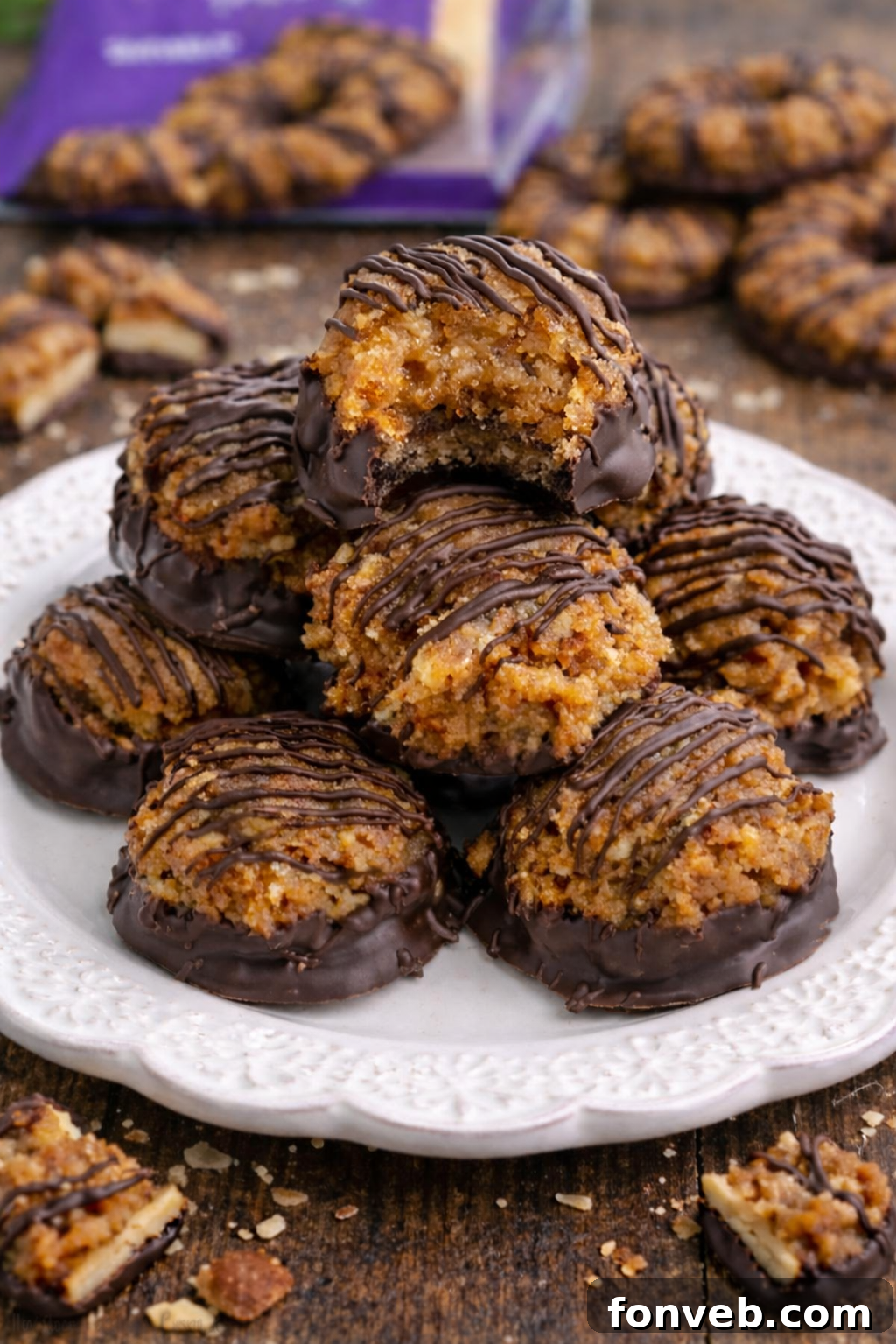 A stack of three Samoa Bites on a white plate, showcasing their chocolate and caramel layers, with more truffles blurred in the background.