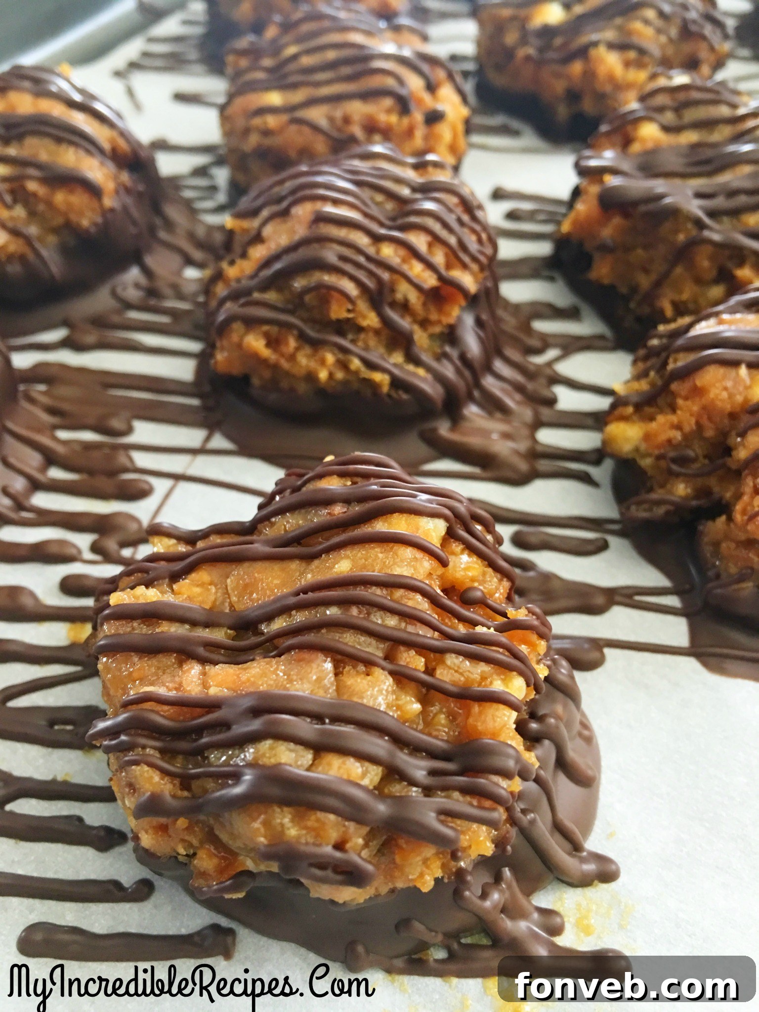 A close-up of Samoa Bites on a parchment paper-lined baking sheet, fully decorated with chocolate coating and elegant drizzles, ready to be enjoyed.