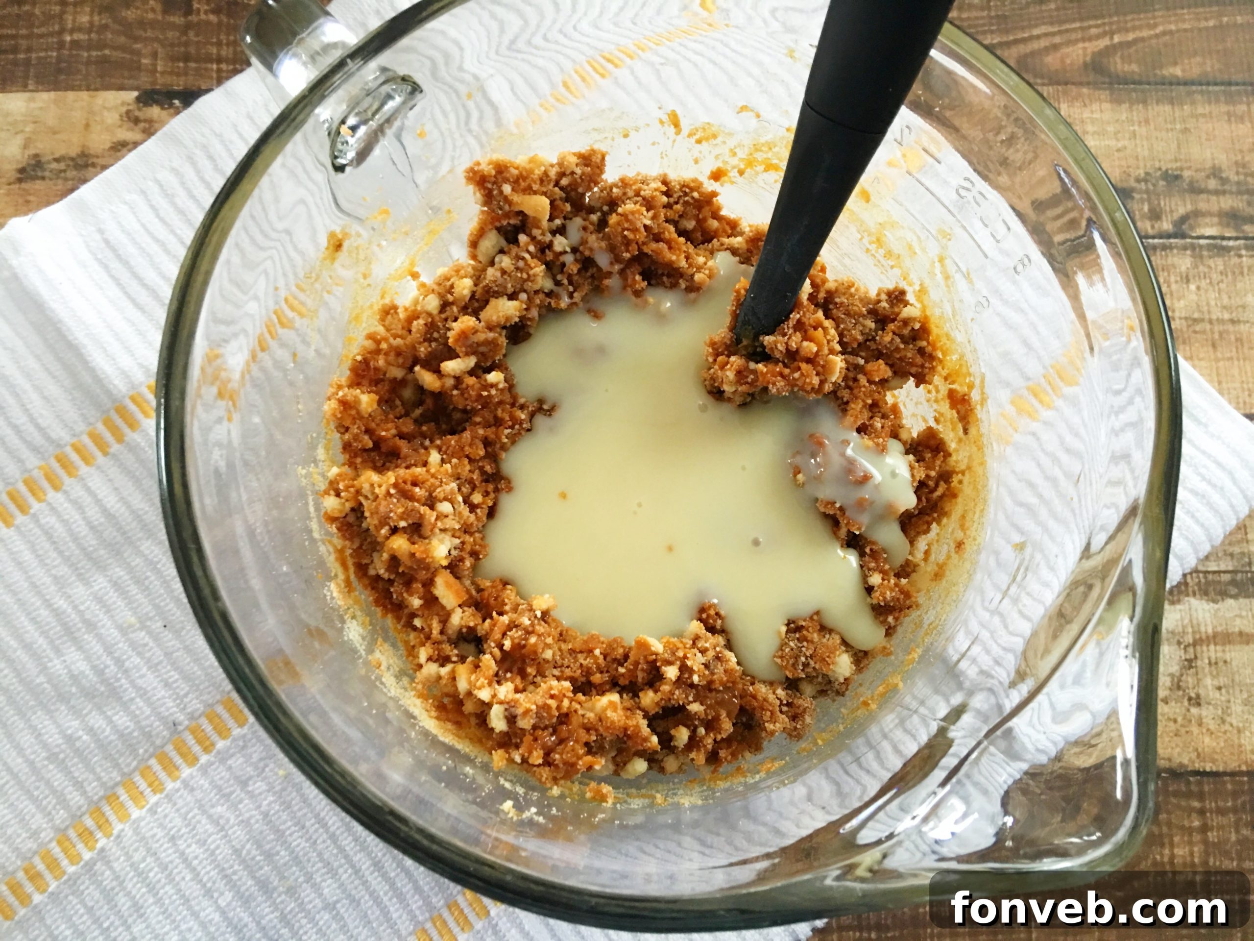 Dulce de leche being added to a large glass mixing bowl filled with the Samoa Bite base mixture, ready to be incorporated.