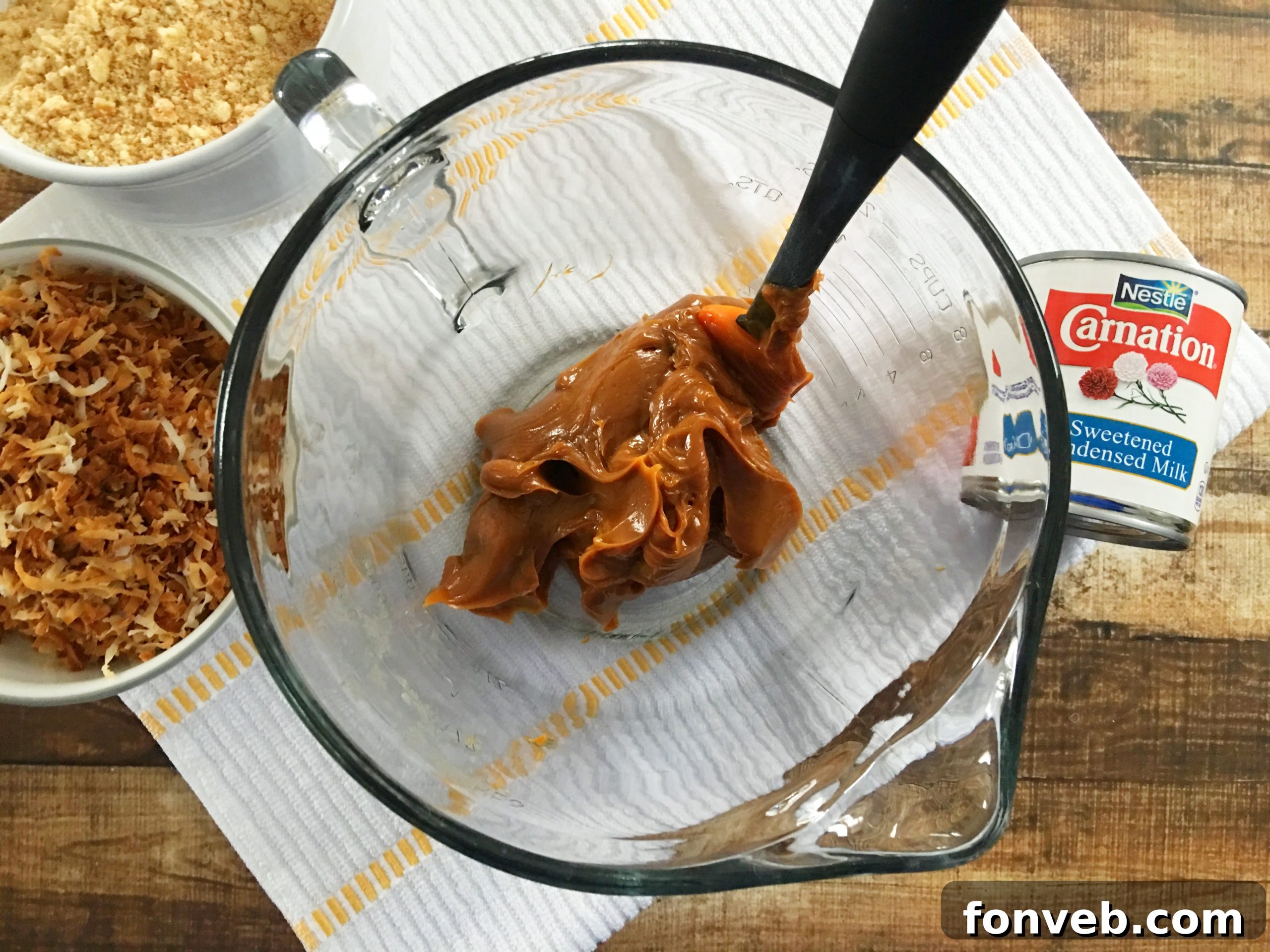The Samoa Bites mixture being stirred in a mixing bowl, showcasing the rich, gooey texture created by the caramel and other ingredients.