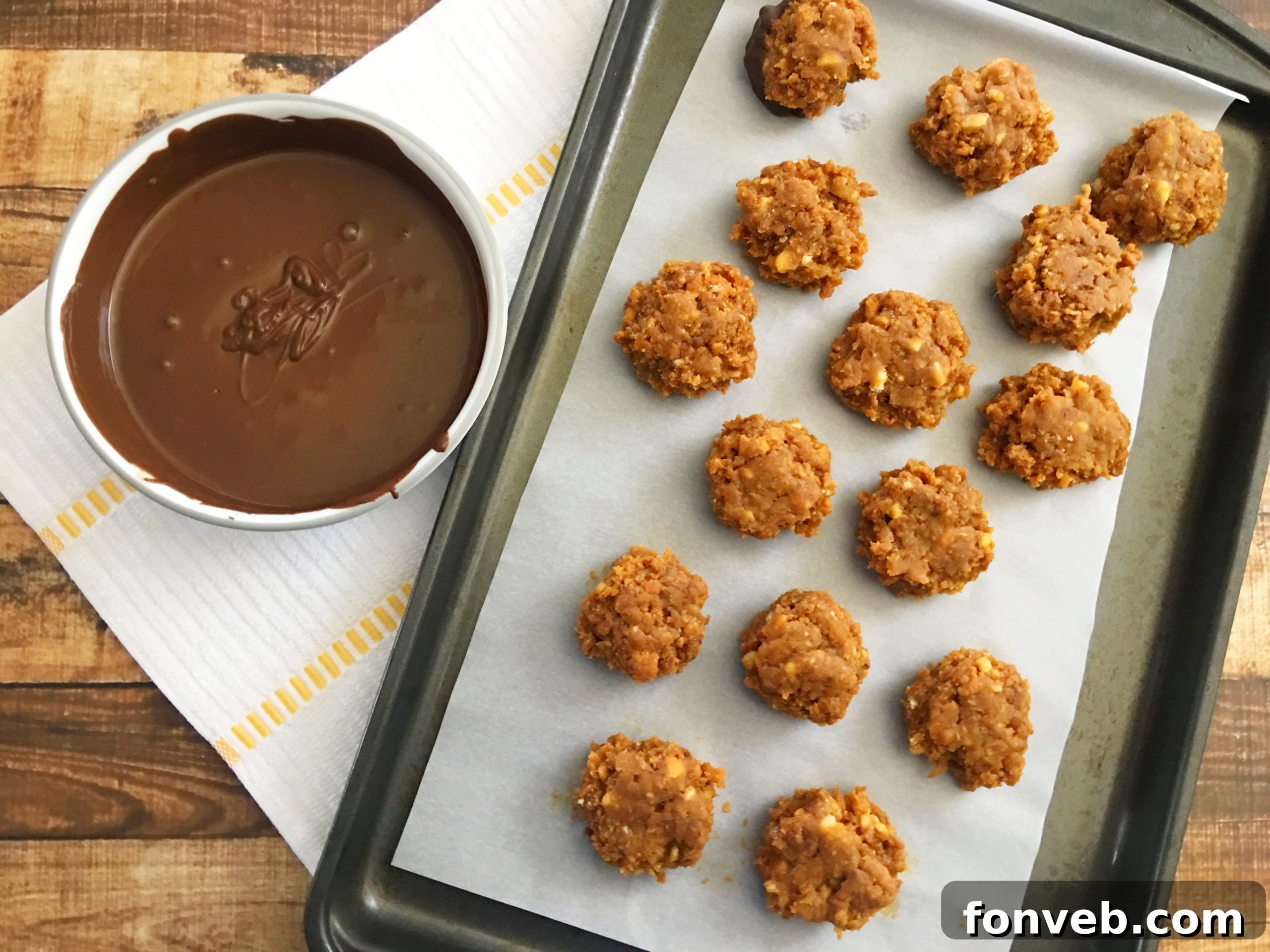 Rows of perfectly shaped Samoa Bites, yet to be dipped in chocolate, neatly arranged on a parchment paper-lined baking sheet.