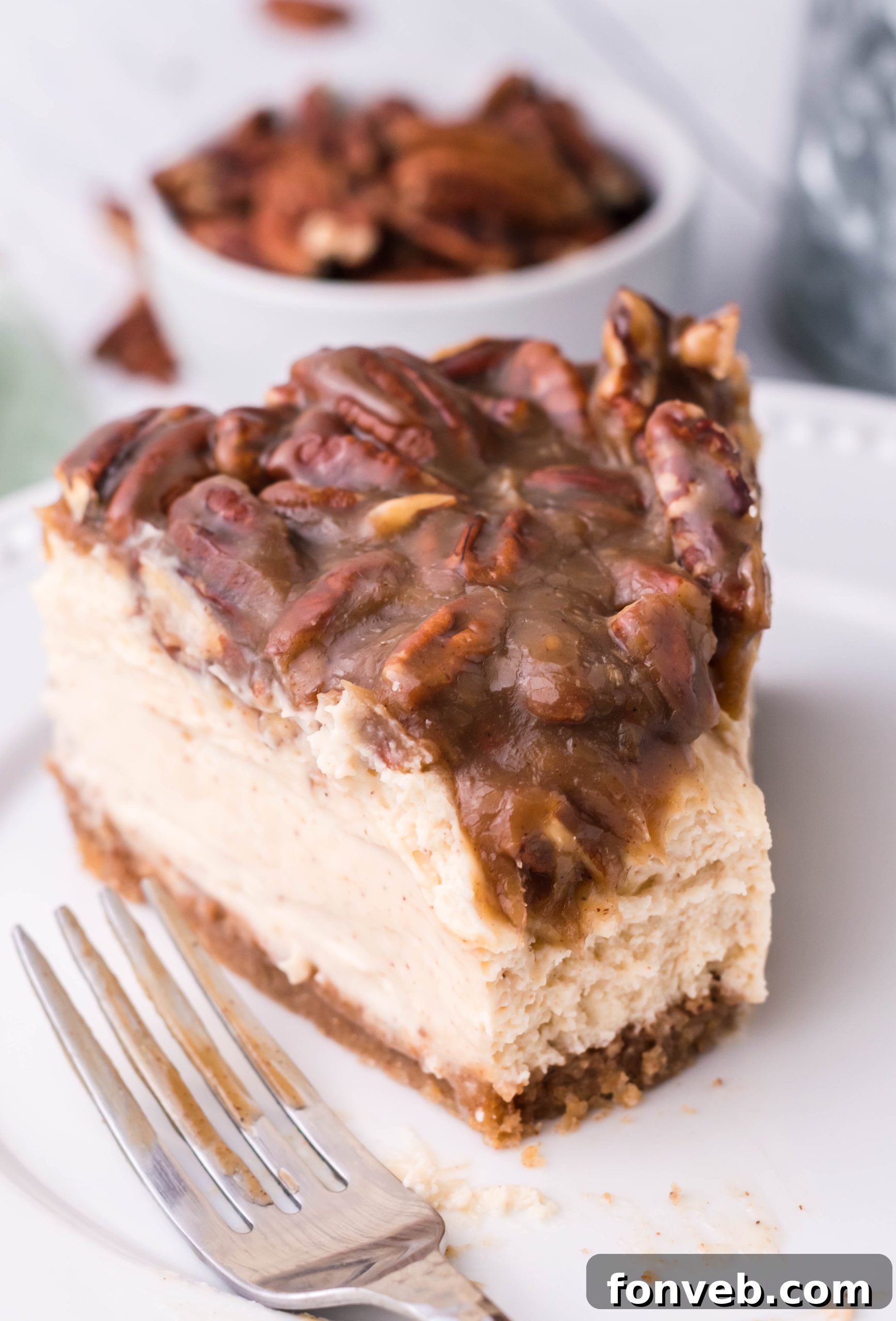 A single, perfectly cut slice of Pecan Pie Cheesecake on a clean white plate, ready to be enjoyed.