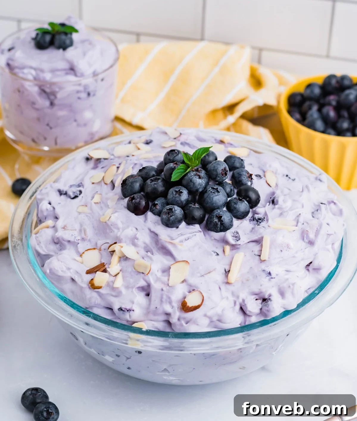 Blueberry Fluff Salad in a clear glass serving bowl topped with blueberries and chopped almonds