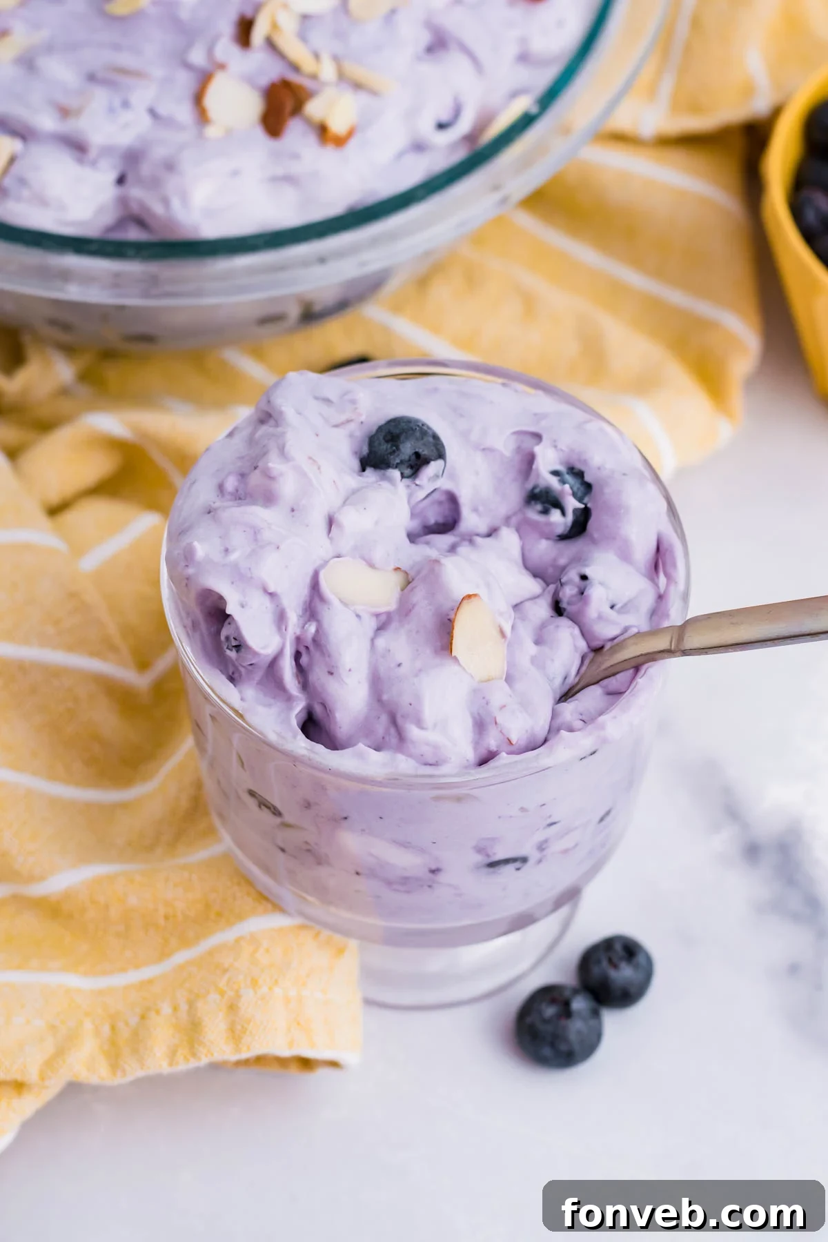 Blueberry Fluff Salad in a clear glass mini trifle with a spoon inside