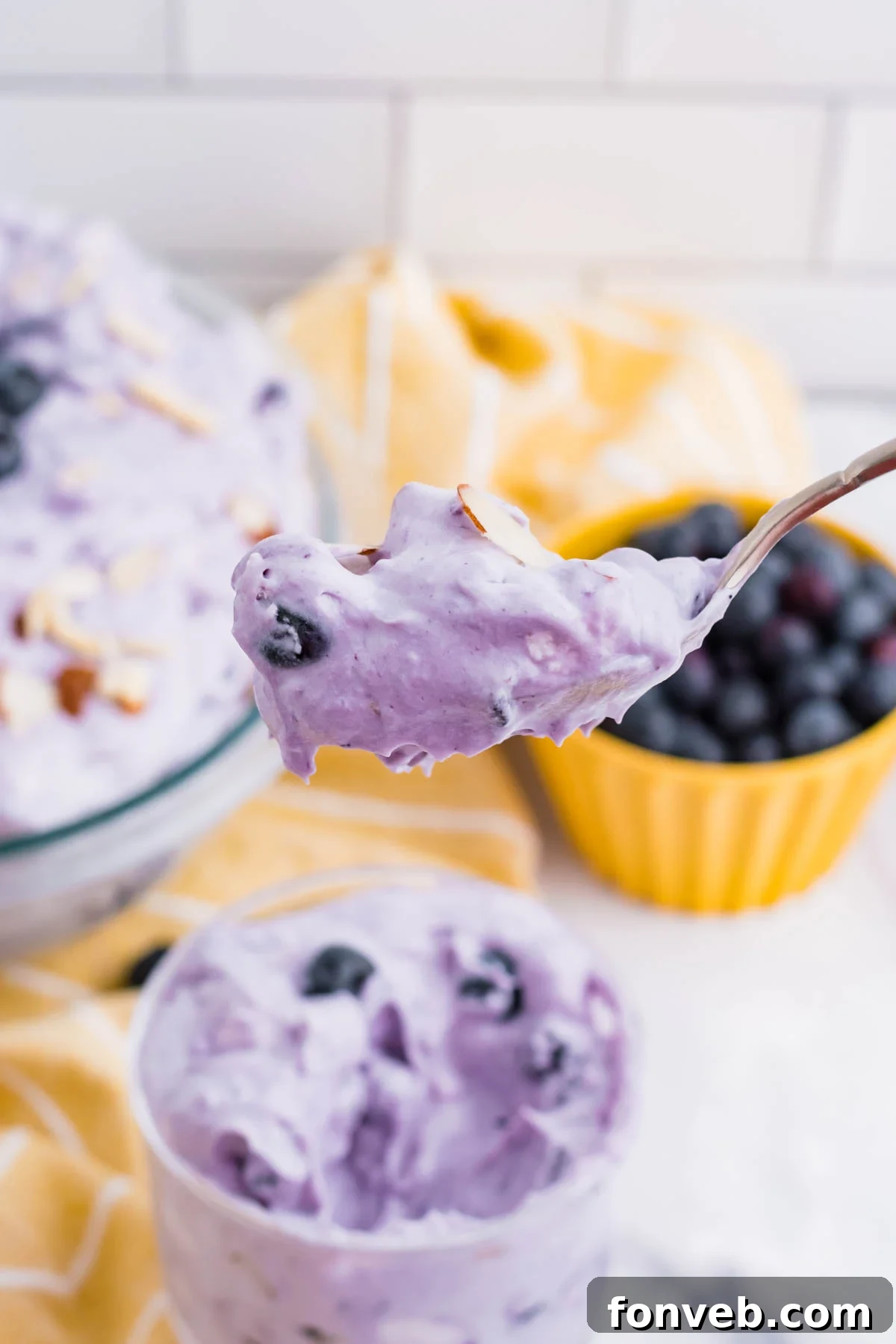 Blueberry Fluff Salad in a clear glass mini trifle with a spoon lifting up a big bite