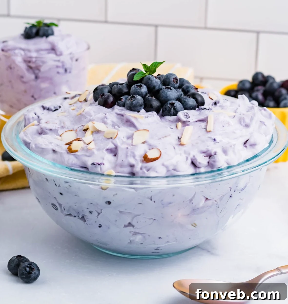Blueberry Fluff Salad in a clear glass serving bowl topped with fresh blueberries