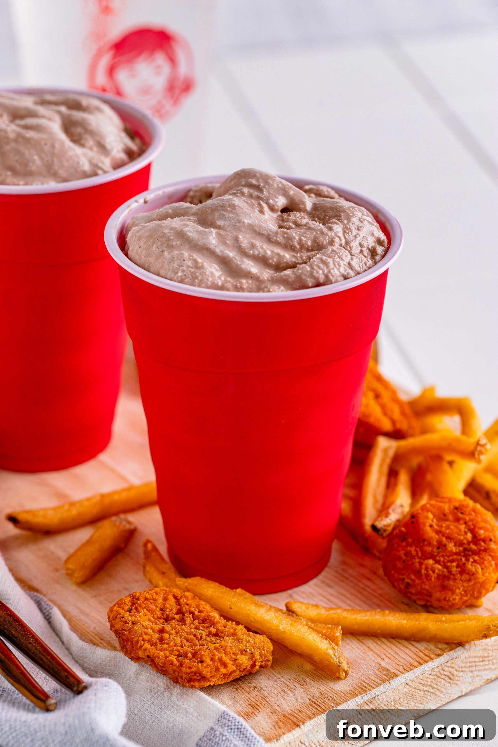 Homemade Wendy's Frosty in a red solo cup, surrounded by crispy chicken nuggets and fries