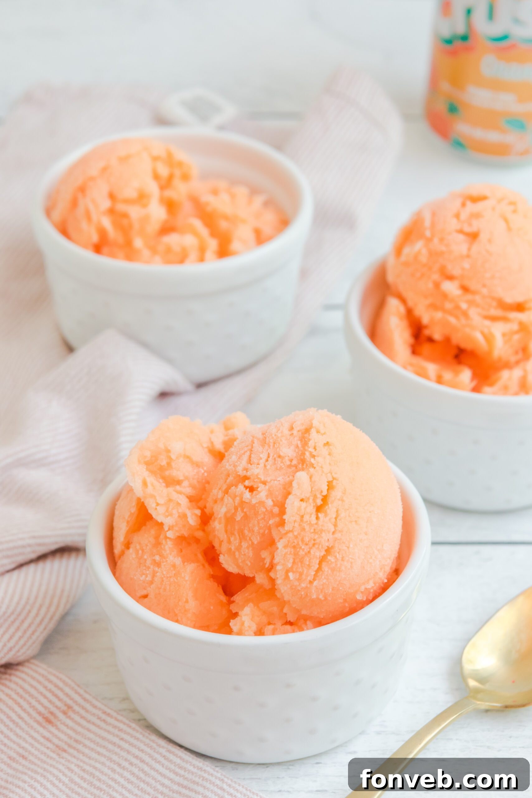 Three white bowls filled with Orange Crush Sherbet, ready to be devoured