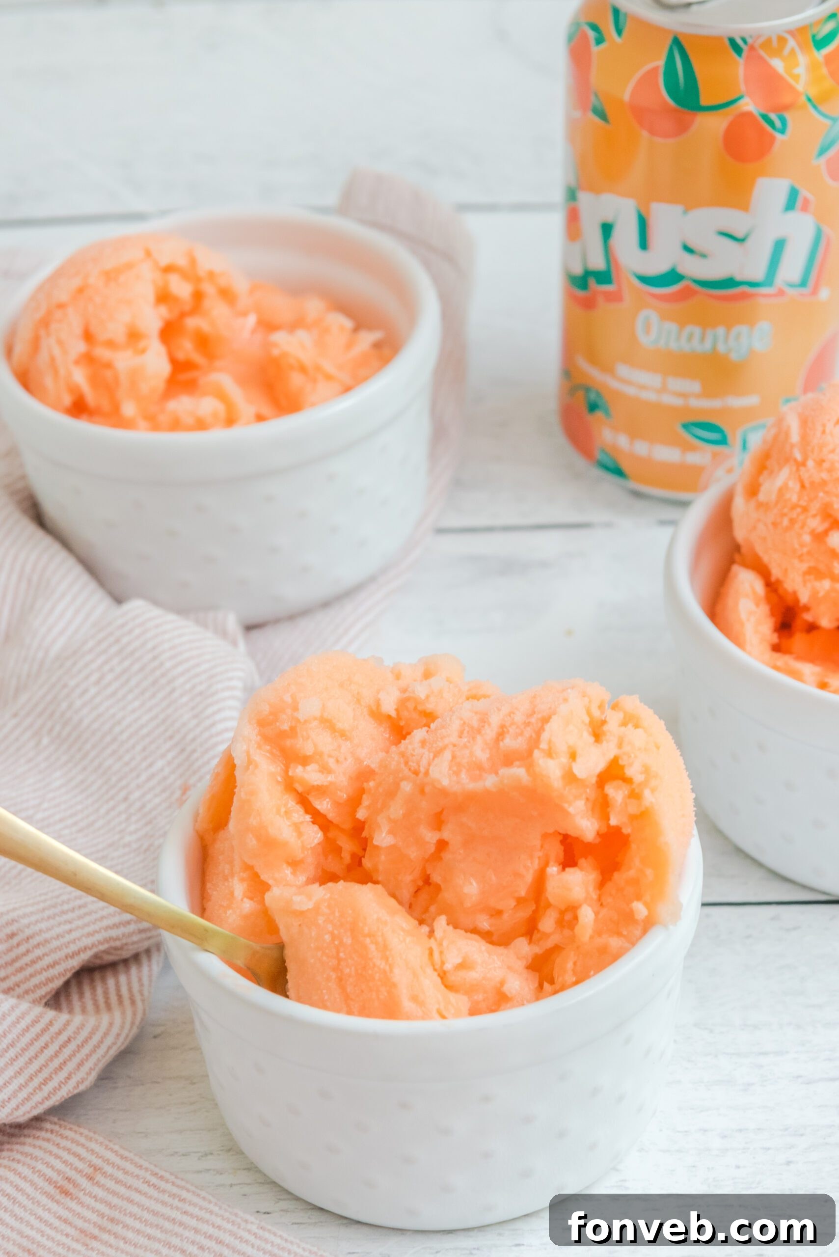 Orange Crush Sherbet in a white bowl with a elegant gold spoon, inviting a taste