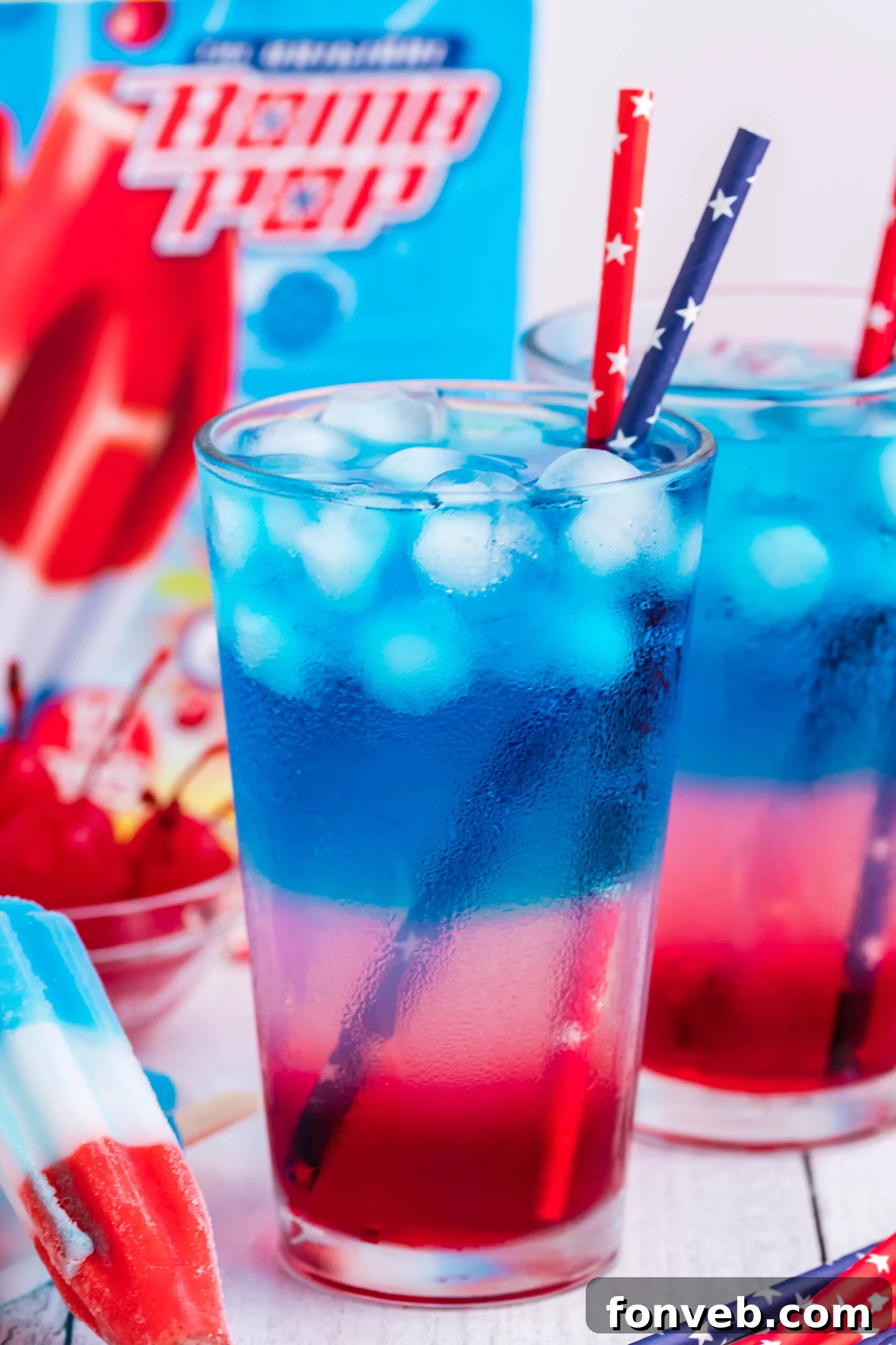 Bomb Pop Cocktail Drink in a clear glass with a blue & red straw side view