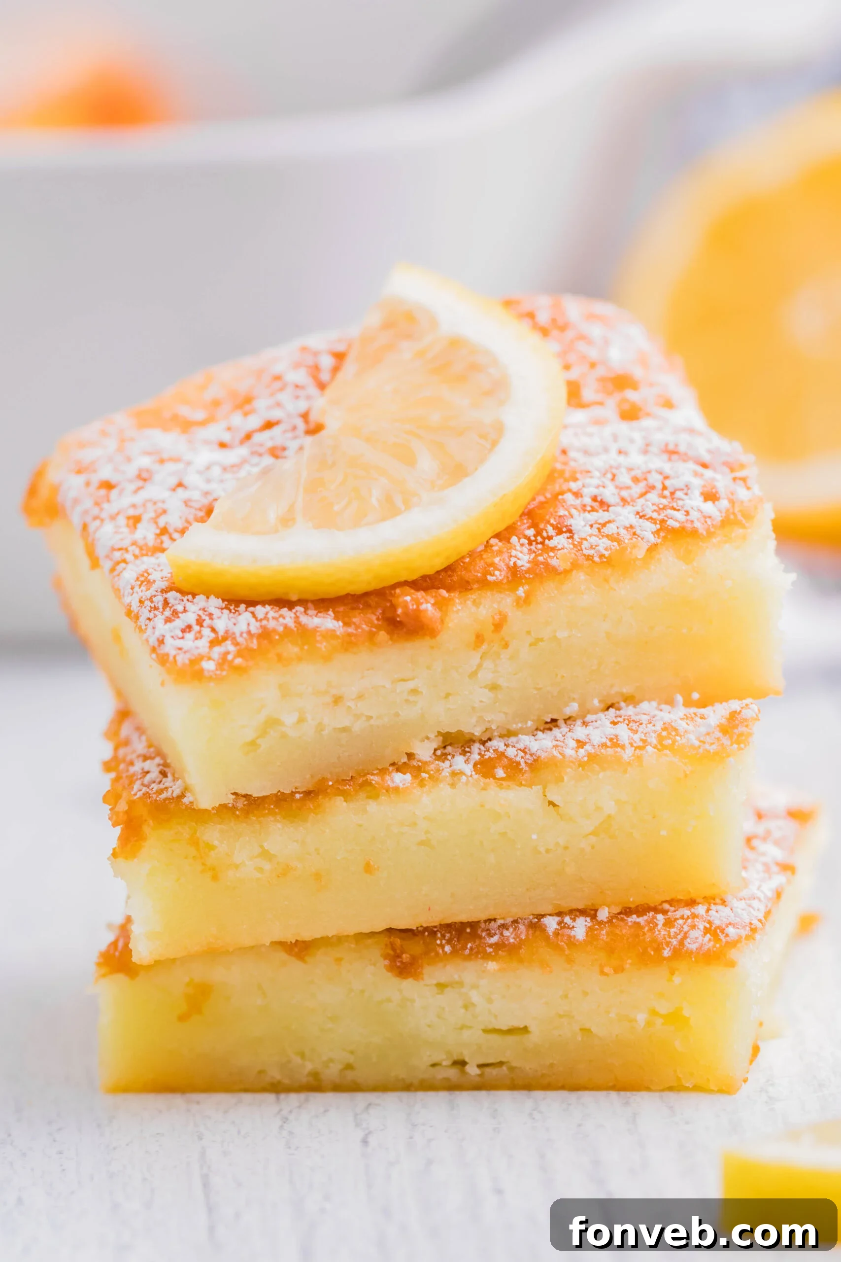 2 Ingredient Lemon Bars stacked with a sliced lemon on top