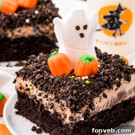 A festive Halloween Dirt Cake adorned with ghost peeps and candy pumpkins, presented in a round, cropped image.