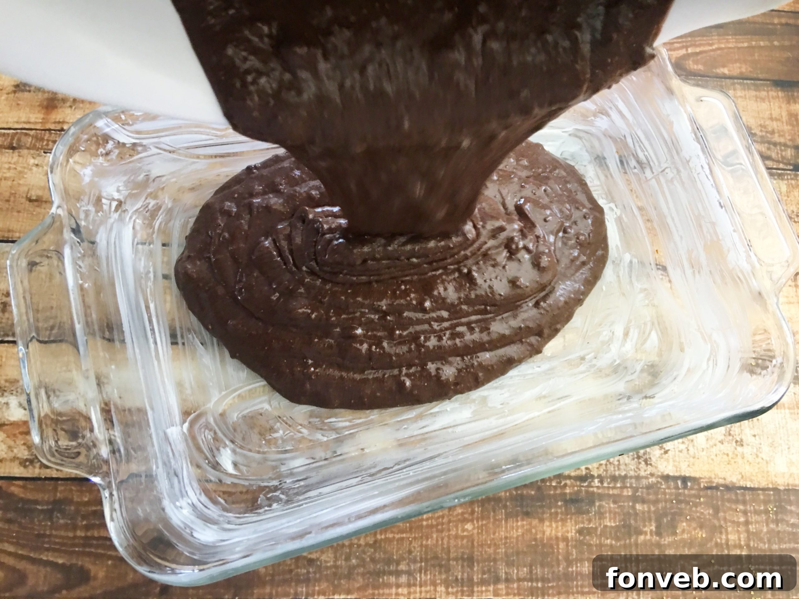 Chocolate cake batter being poured into a baking dish