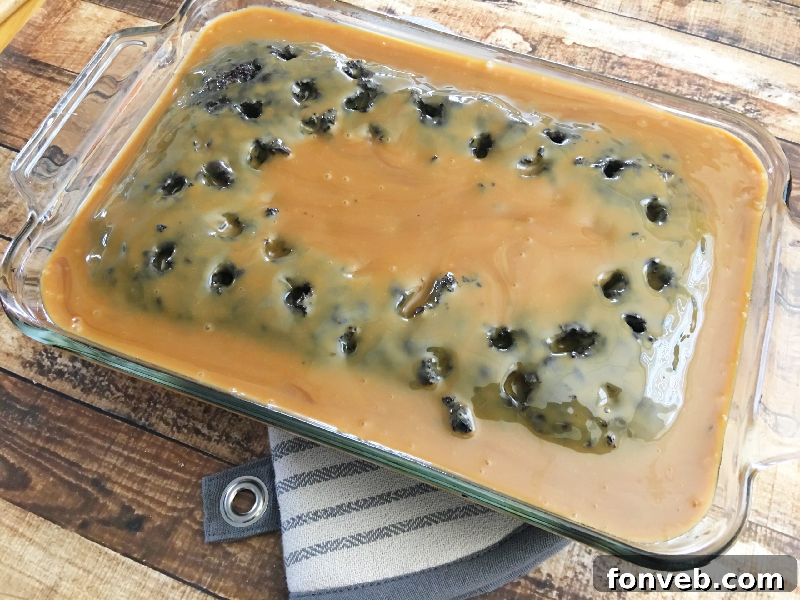 Spreading cool whip frosting evenly over the caramel-infused cake