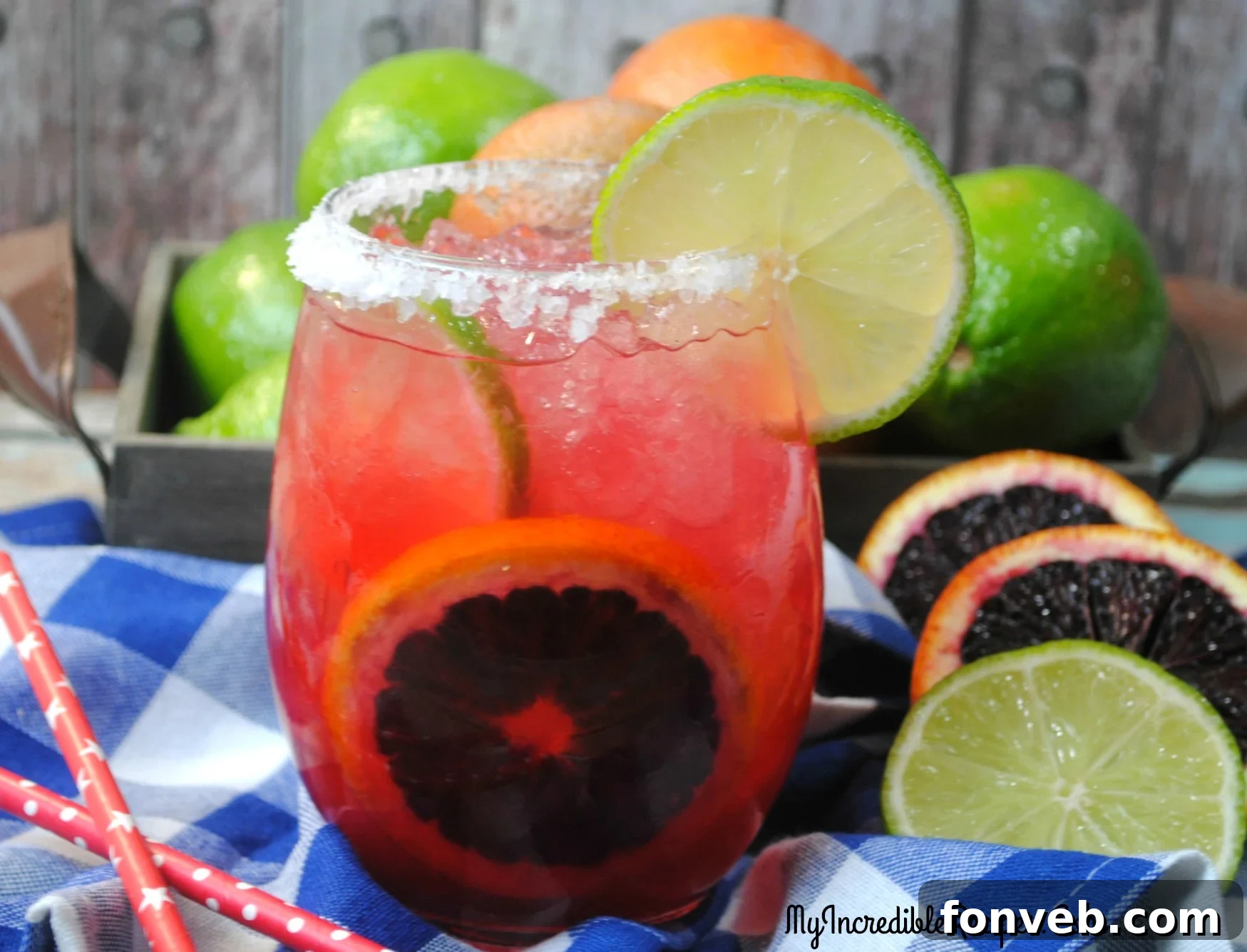 Two glasses of vibrant Blood Orange Margaritas artfully arranged with fresh blood orange slices and lime wedges on a light background, evoking a summer vibe.
