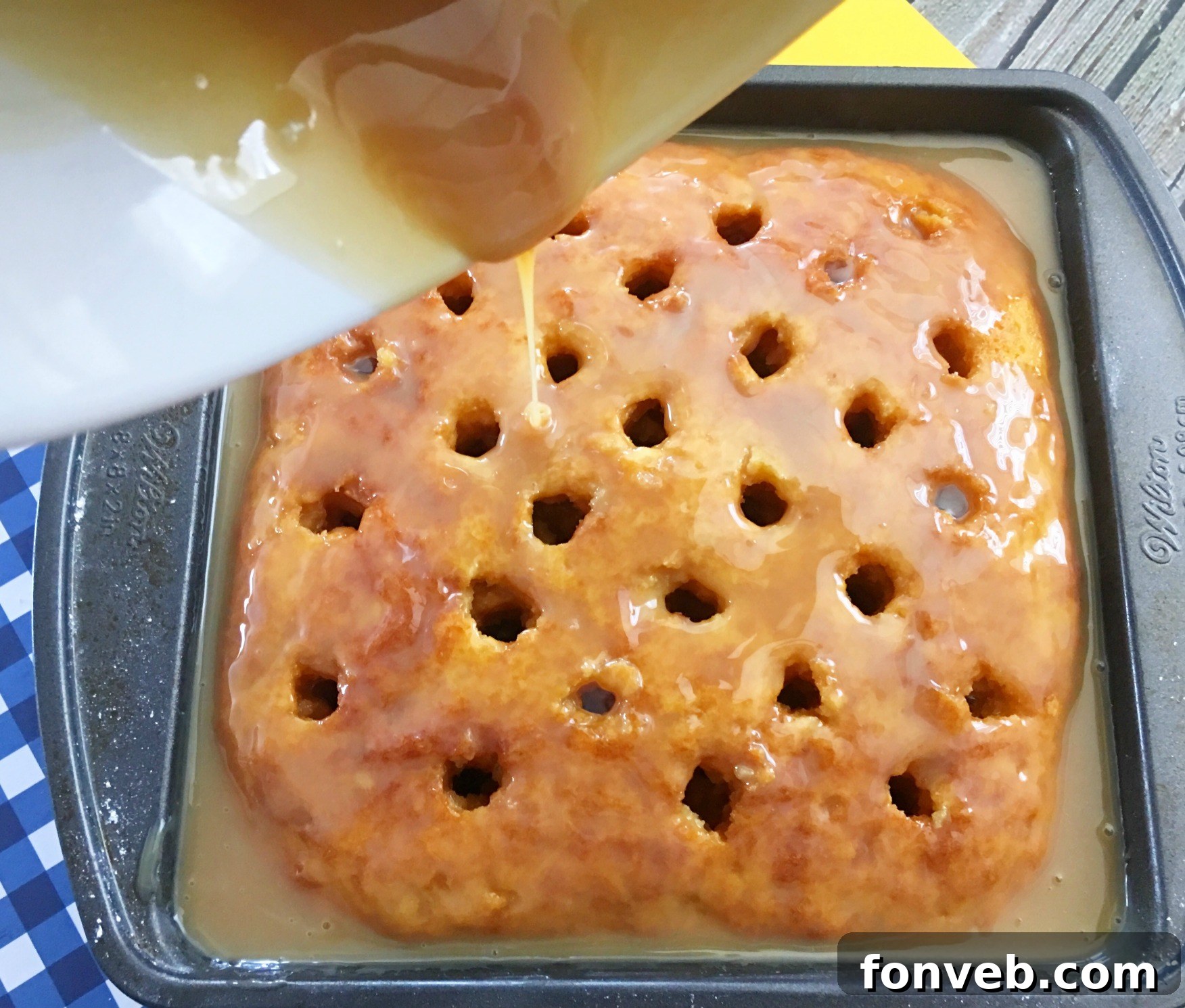 A freshly baked cake with numerous holes poked into its surface, ready to absorb the delicious liquid.