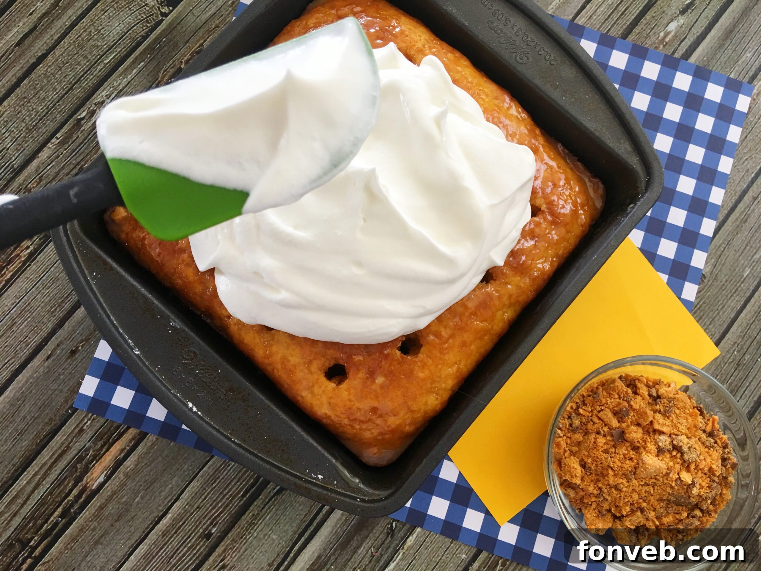A close-up shot of the cake, with the caramel and condensed milk mixture generously poured into the poked holes, soaking in.