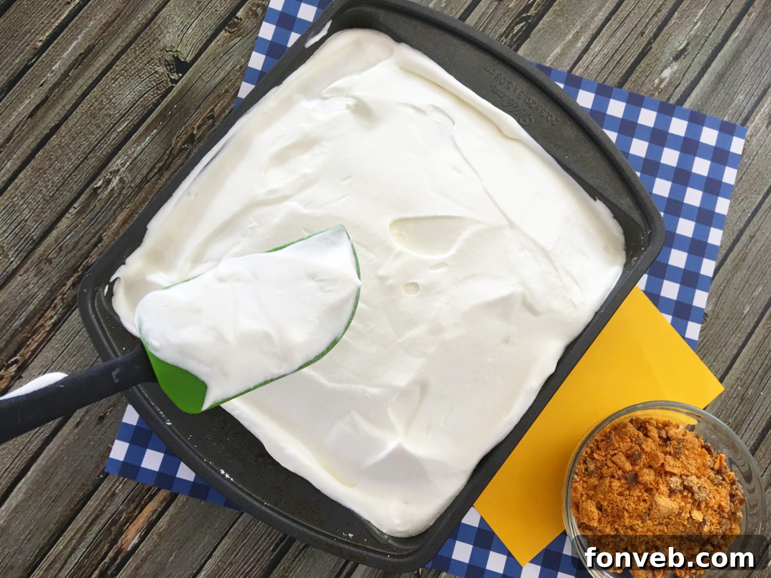 Smooth, fluffy whipped cream being spread evenly over the caramel-soaked cake, creating a perfect canvas for toppings.