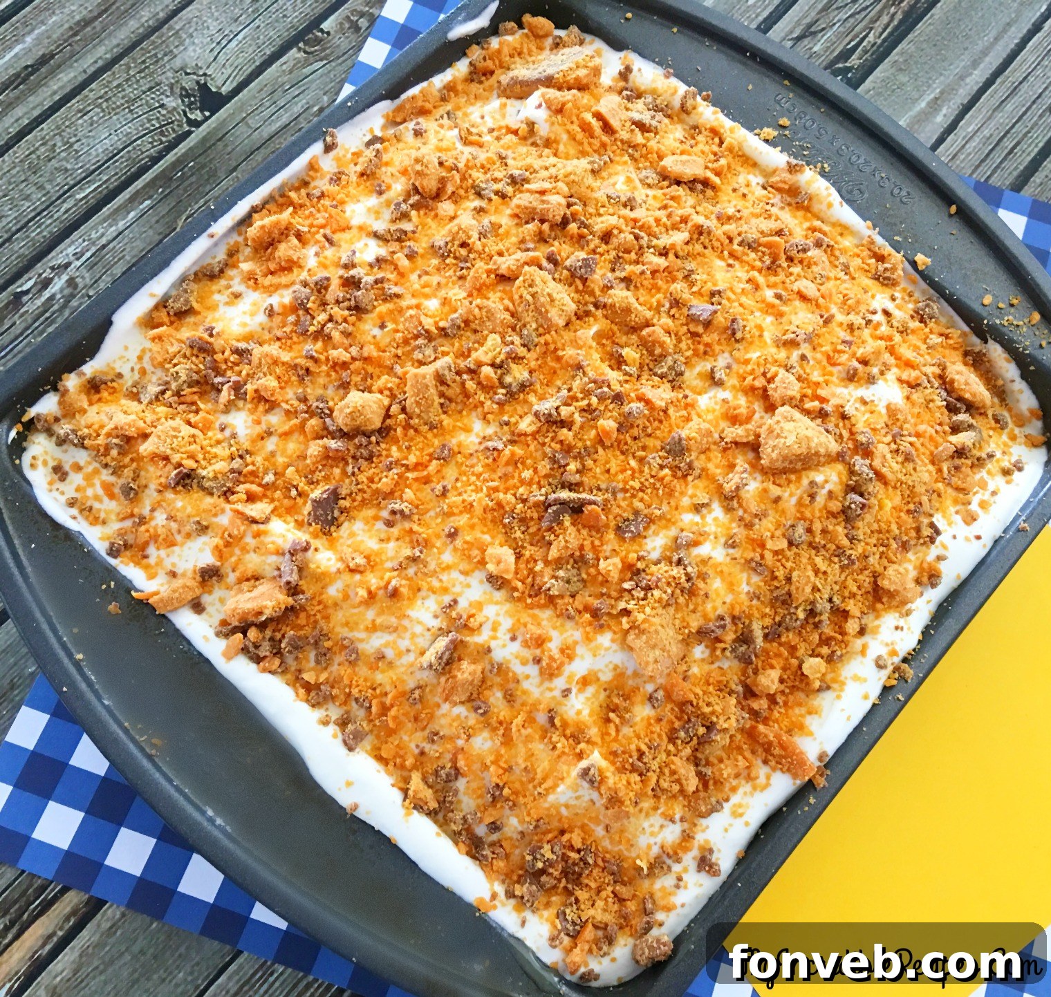 A close-up of the Butterfinger Extasy Cake, showing the smooth whipped cream topping and a hint of the caramel layer underneath.