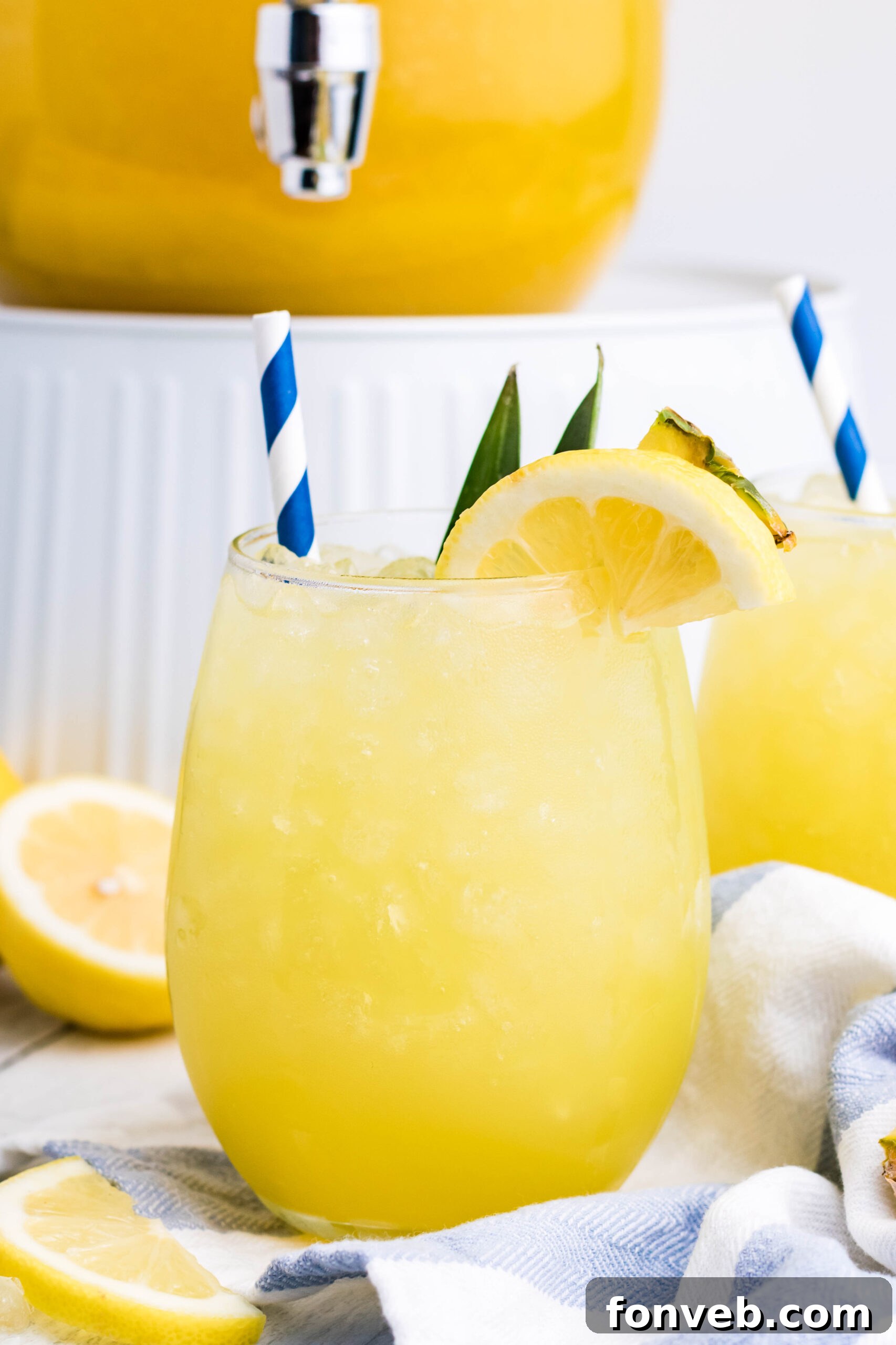 Vibrant Pineapple Lemonade served in a clear glass with ice, garnished with a fresh lemon slice and pineapple wedge