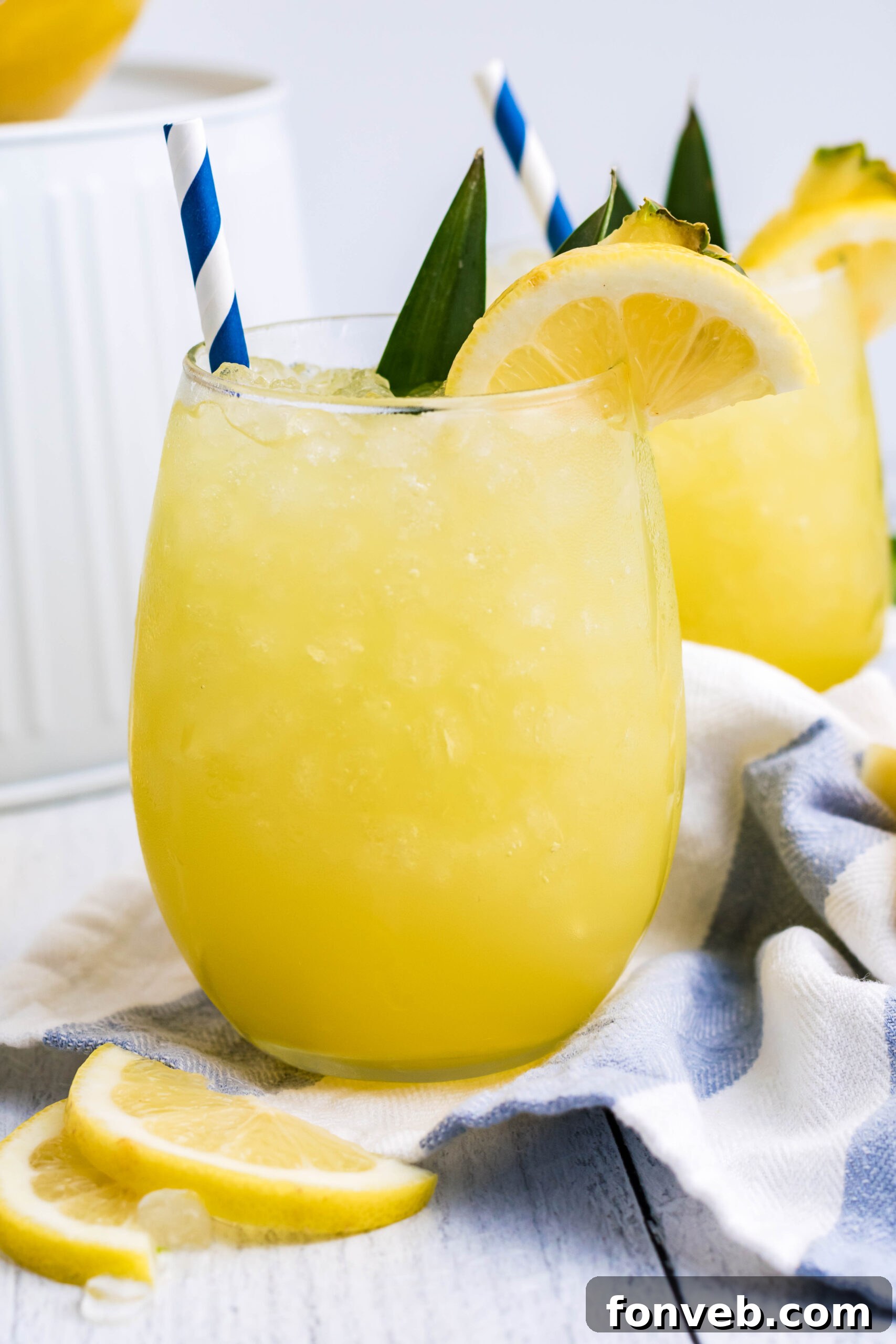 Pineapple Lemonade in a glass with ice and a decorative sliced lemon, emphasizing its fresh ingredients