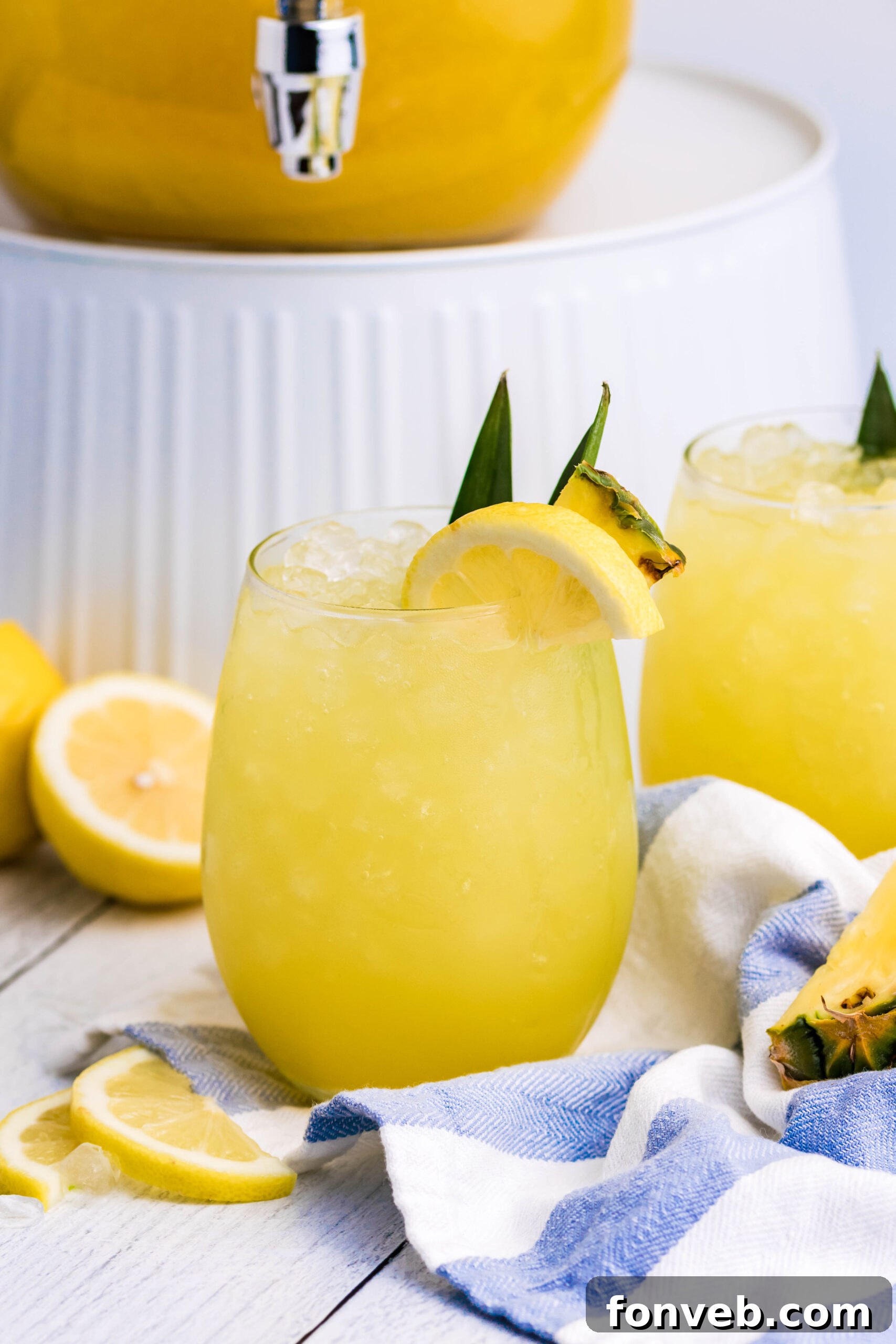 Pineapple Lemonade in a clear glass with ice on a clean white wooden table, focusing on the drink itself