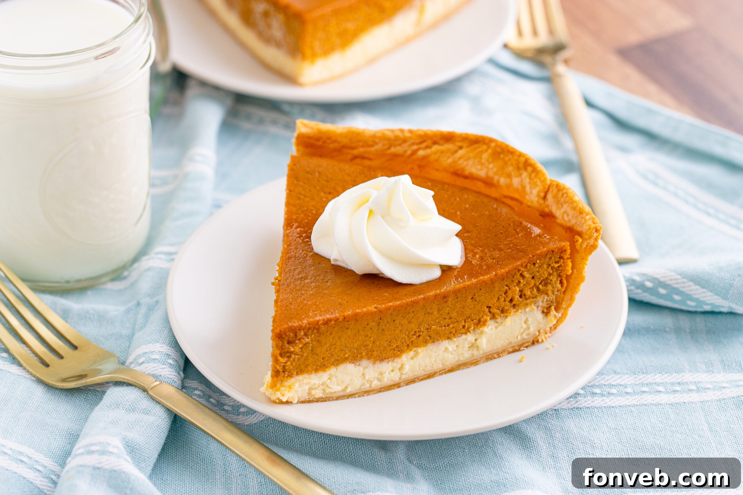 Side angle view of a generous slice of Pumpkin Pie Cheesecake on a white plate, highlighting the distinct cheesecake and pumpkin layers
